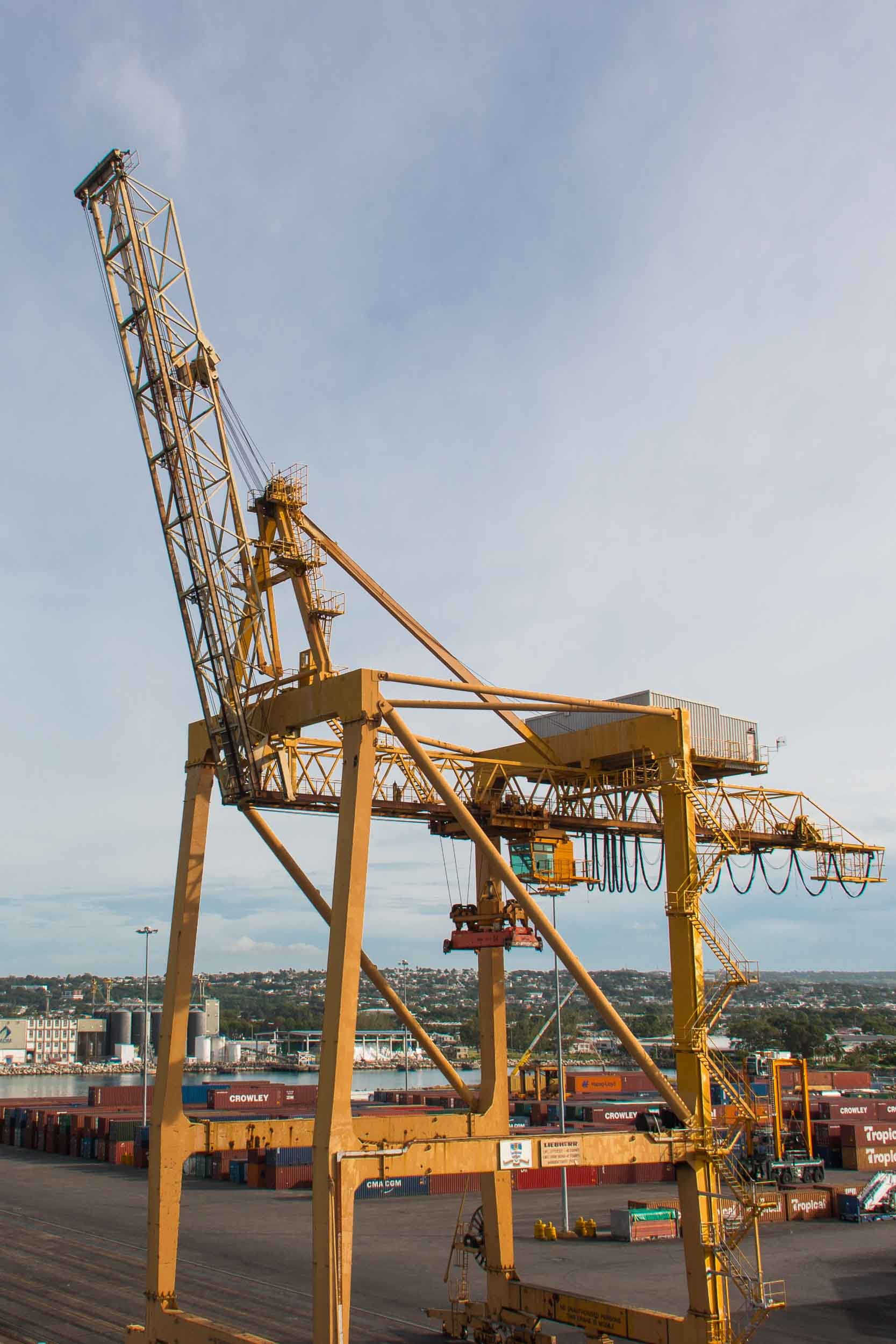 The image features a prominent ship-to-shore (STS) gantry crane at the Port of Bridgetown in Barbados.