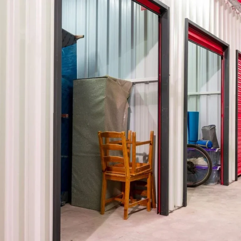 Storage unit with stacked chairs, mattress, and bicycle inside.