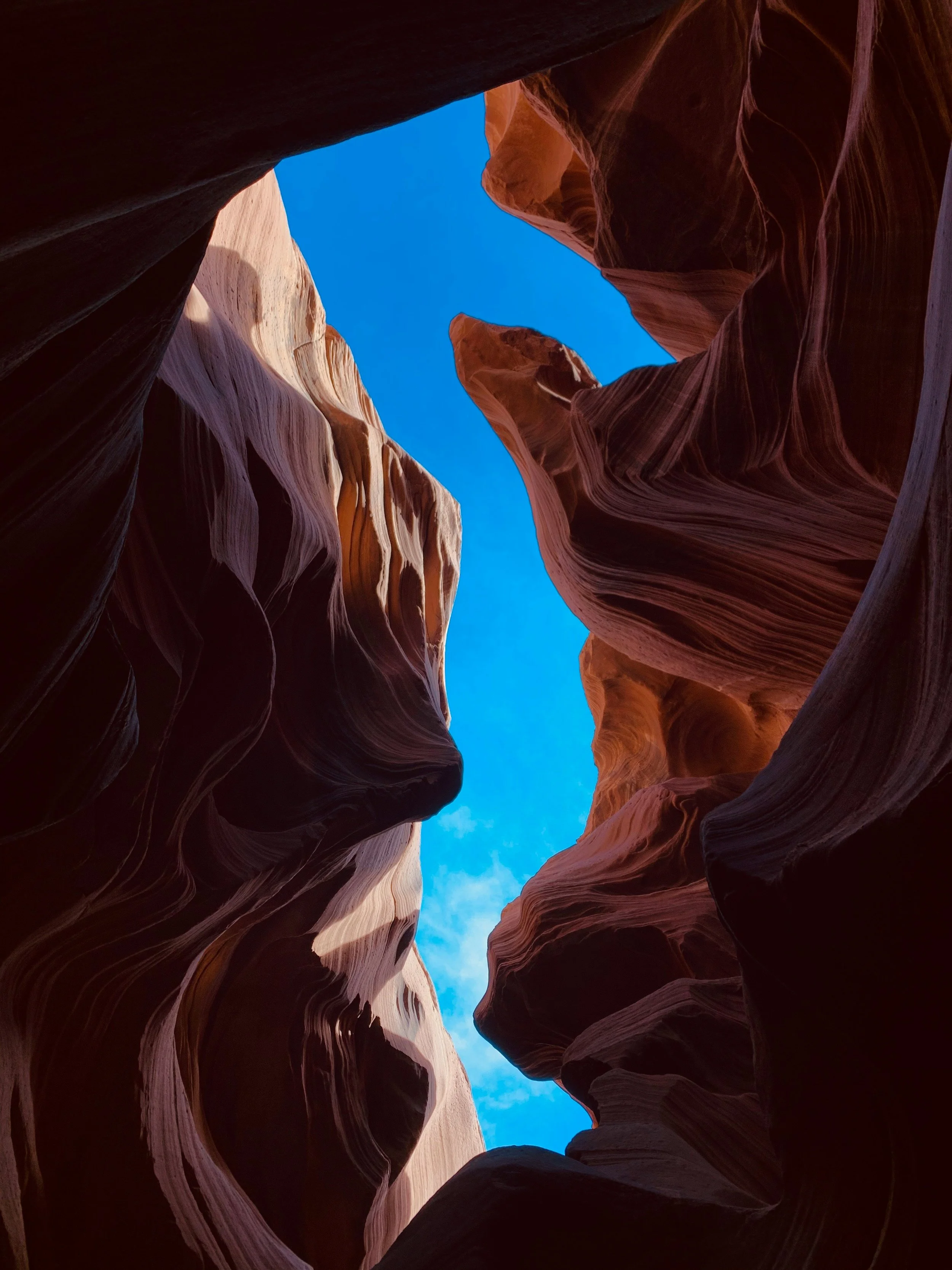 narrow canyon opening toward blue sky, representing perspective, movement and ongoing conversations.