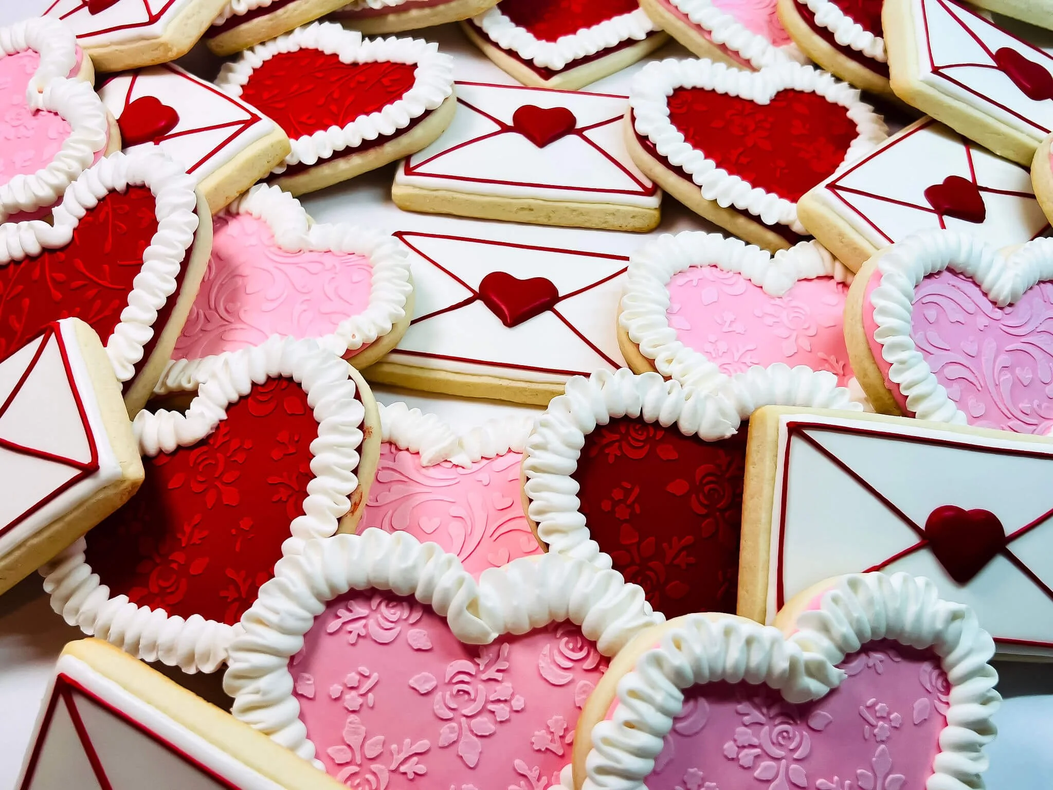 Decorated cookies in various shapes and colors, including red, pink, and white, with Valentine-themed icing and patterns.