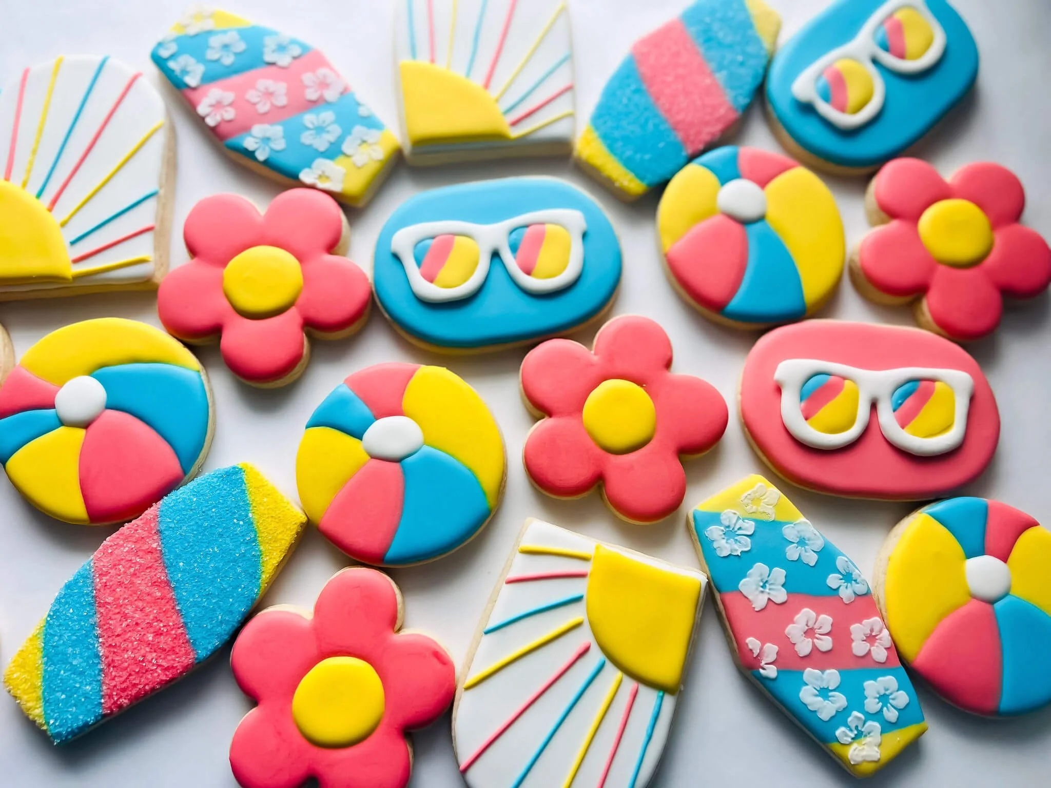 Colorful decorated cookies shaped like flowers, sunglasses, suns, umbrellas, and beach balls.