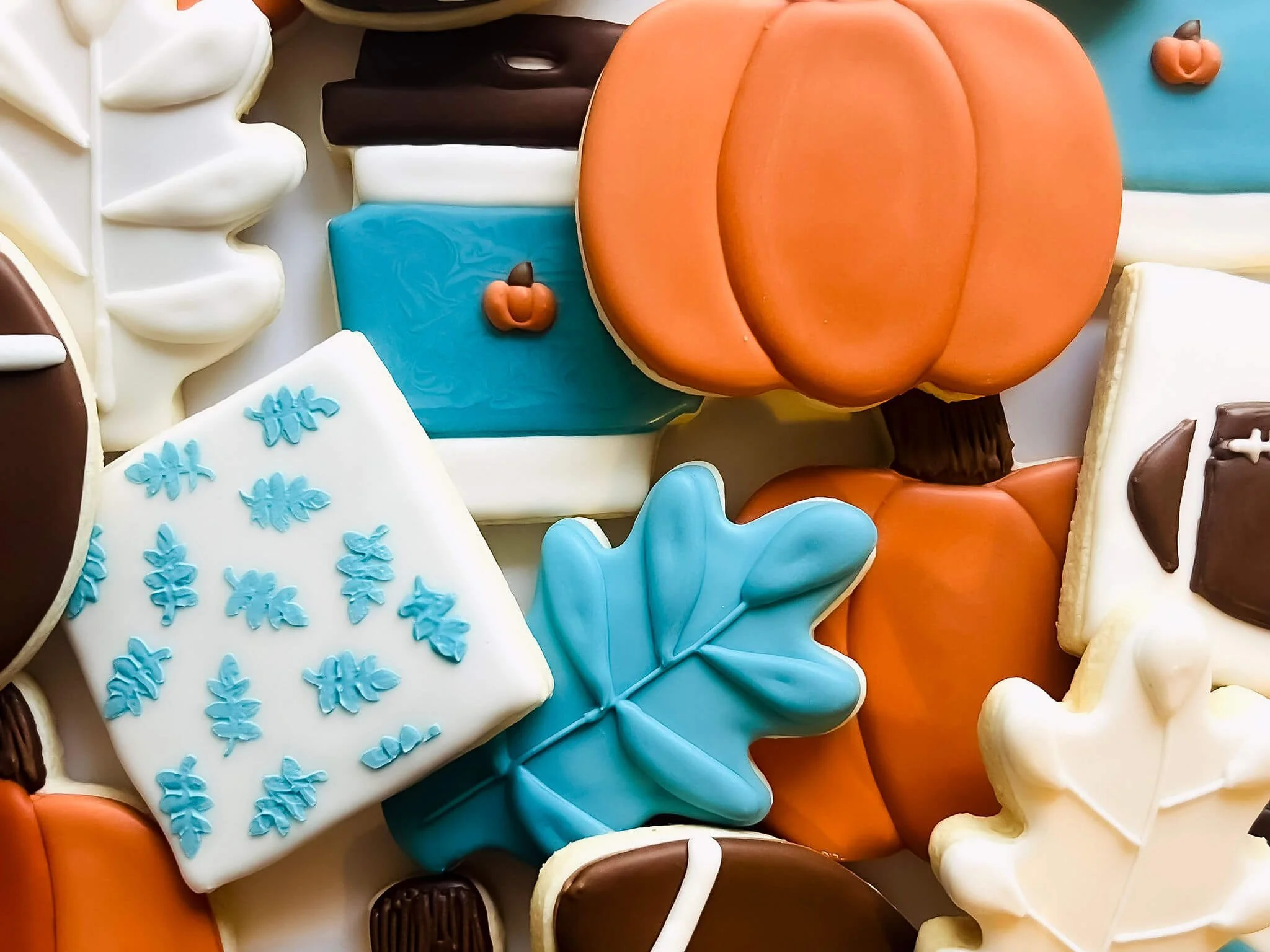 Assorted decorated sugar cookies with fall themes, including pumpkins, leaves, and acorns.