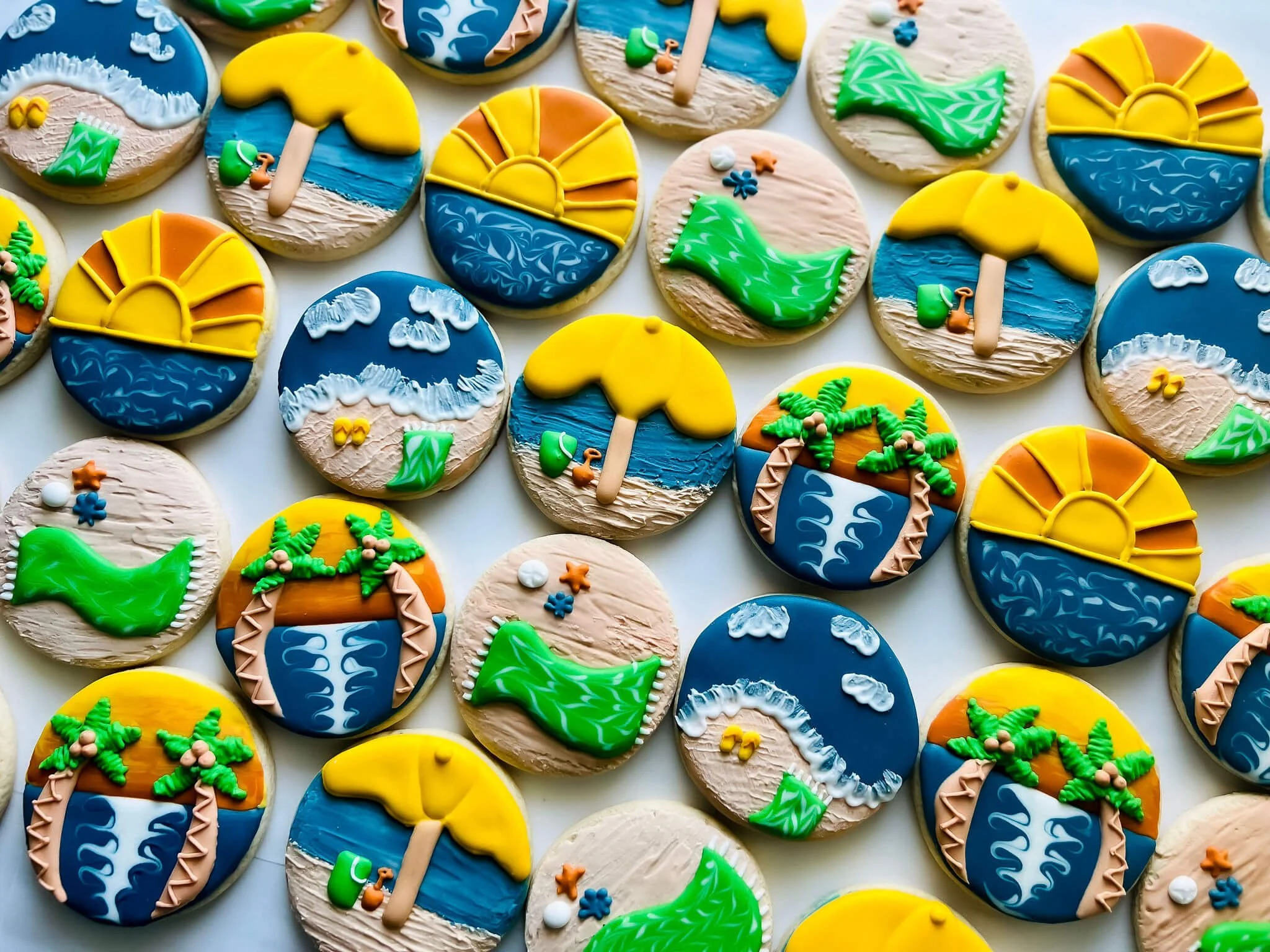 Decorated cookies with beach and summer theme, featuring umbrellas, waves, and tropical plants.