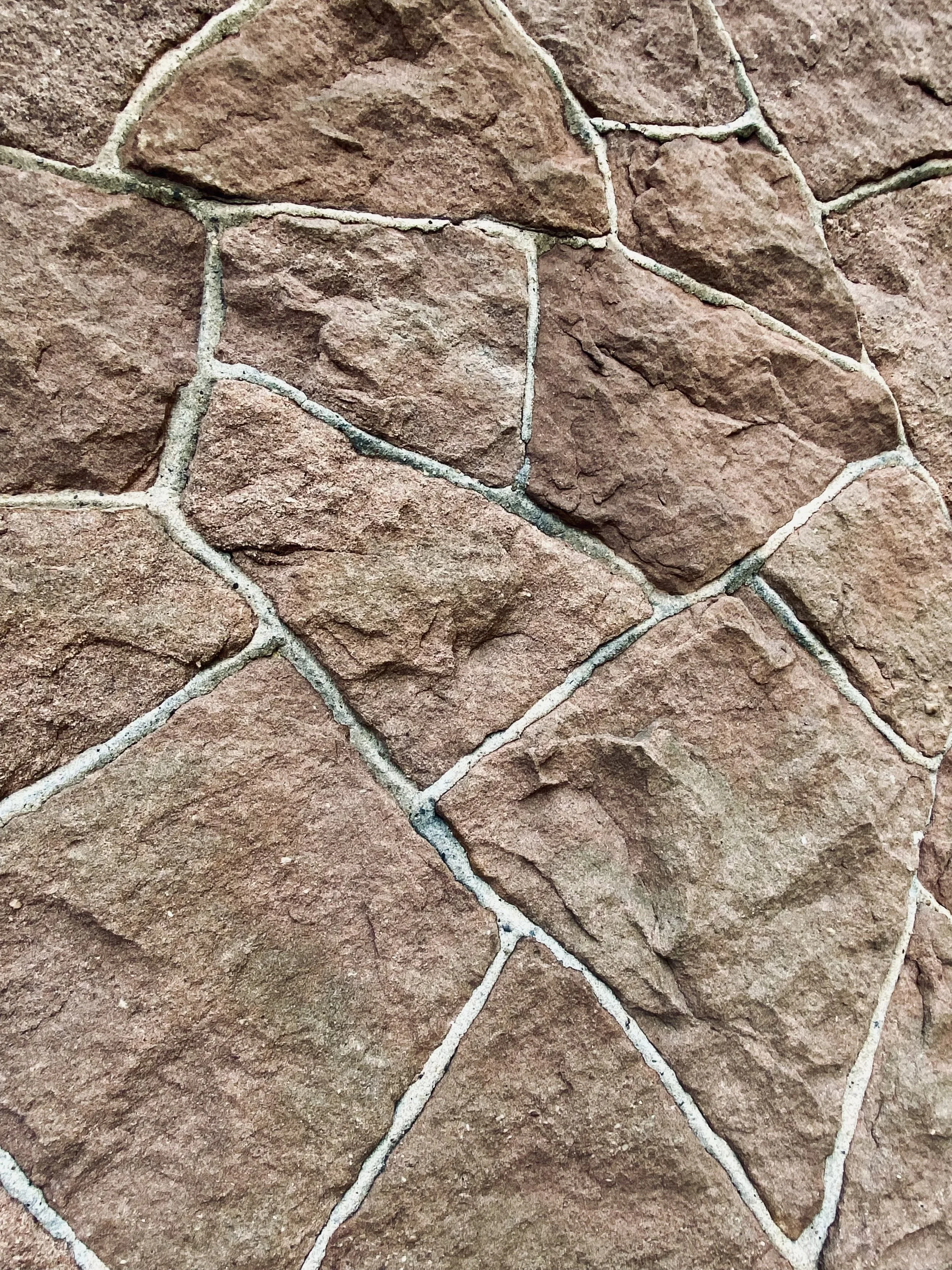 Close-up of red brick wall with light gray mortar lines forming irregular shapes.