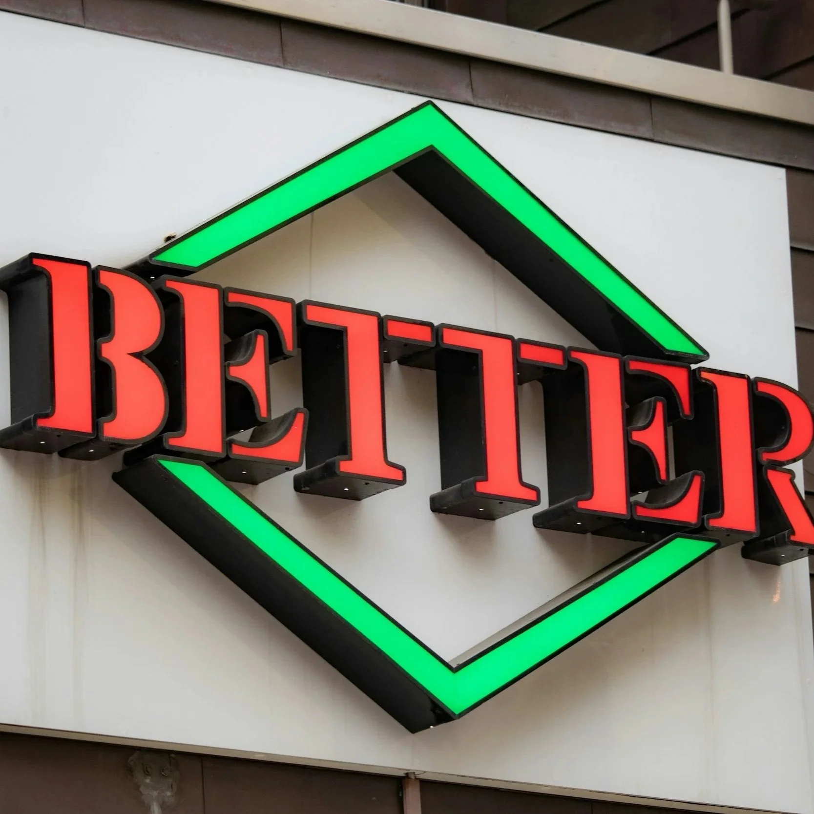 Neon sign reading 'Bettier' in red letters with a green geometric border.
