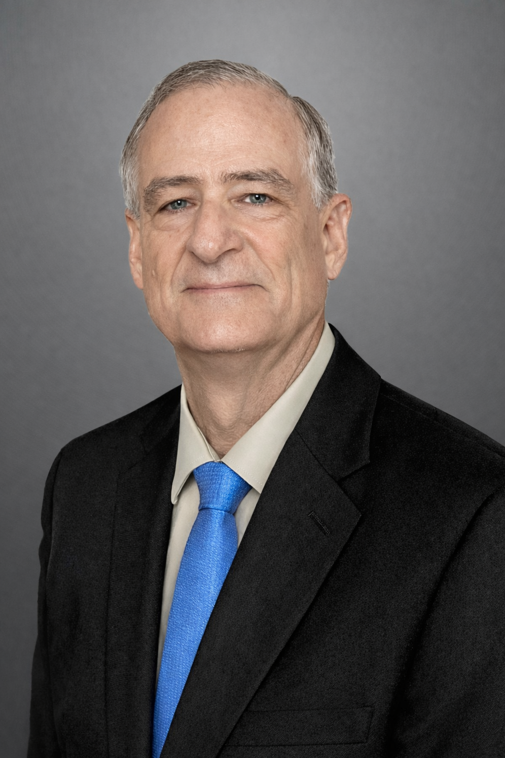 Instructor Blake McConnell. A middle-aged man with gray hair, blue eyes, and light skin wearing a black suit, white shirt, and blue tie, posing against a gray background.