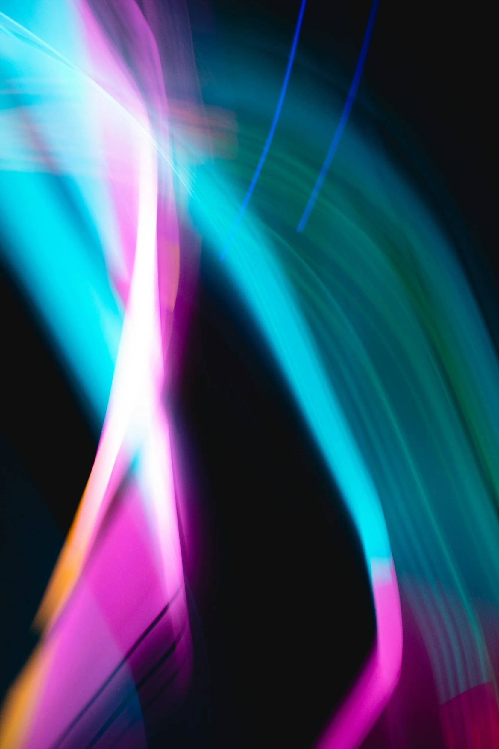 Abstract background with flowing neon lights in pink, blue, and green colors against a black backdrop.