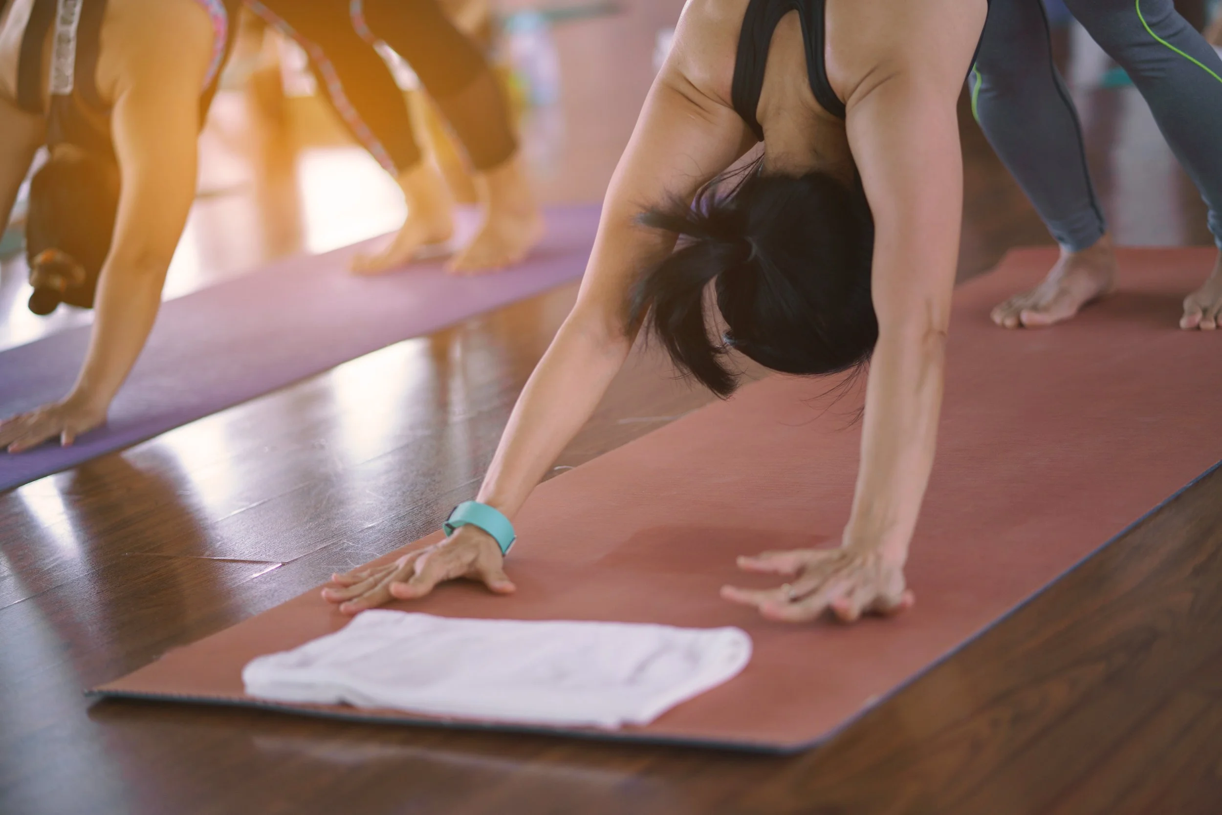 Groupe de personnes pratiquant le yoga en position de planche sur des tapis de yoga, dans une salle claire et chaleureuse.
