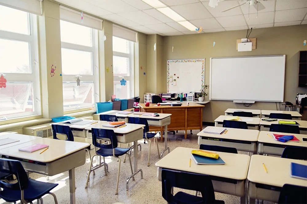 Empty classroom with desks, chairs, notebooks, pencils, and a whiteboard. Classroom Safety.
