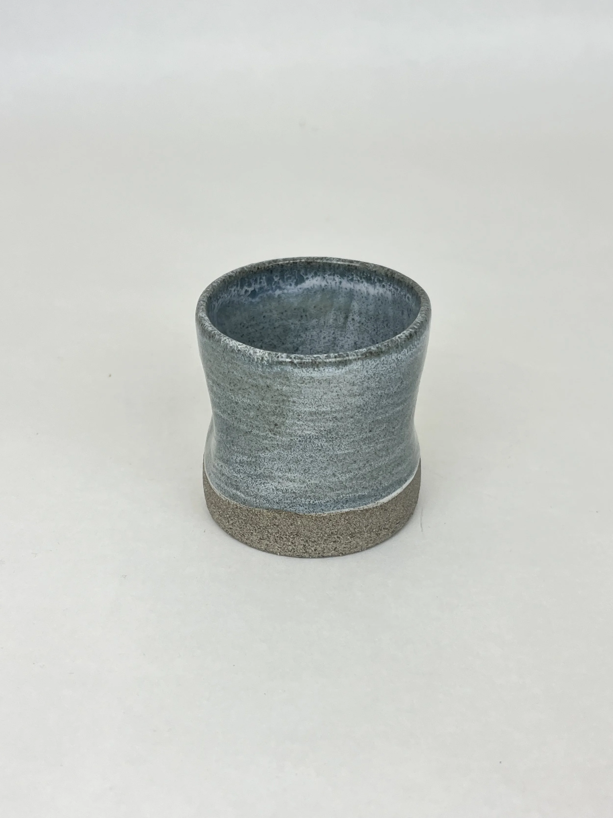 Kleine Keramikvase mit glatter Oberfläche und einer Farbverlauf von Grau nach Beige, auf weißem Hintergrund.