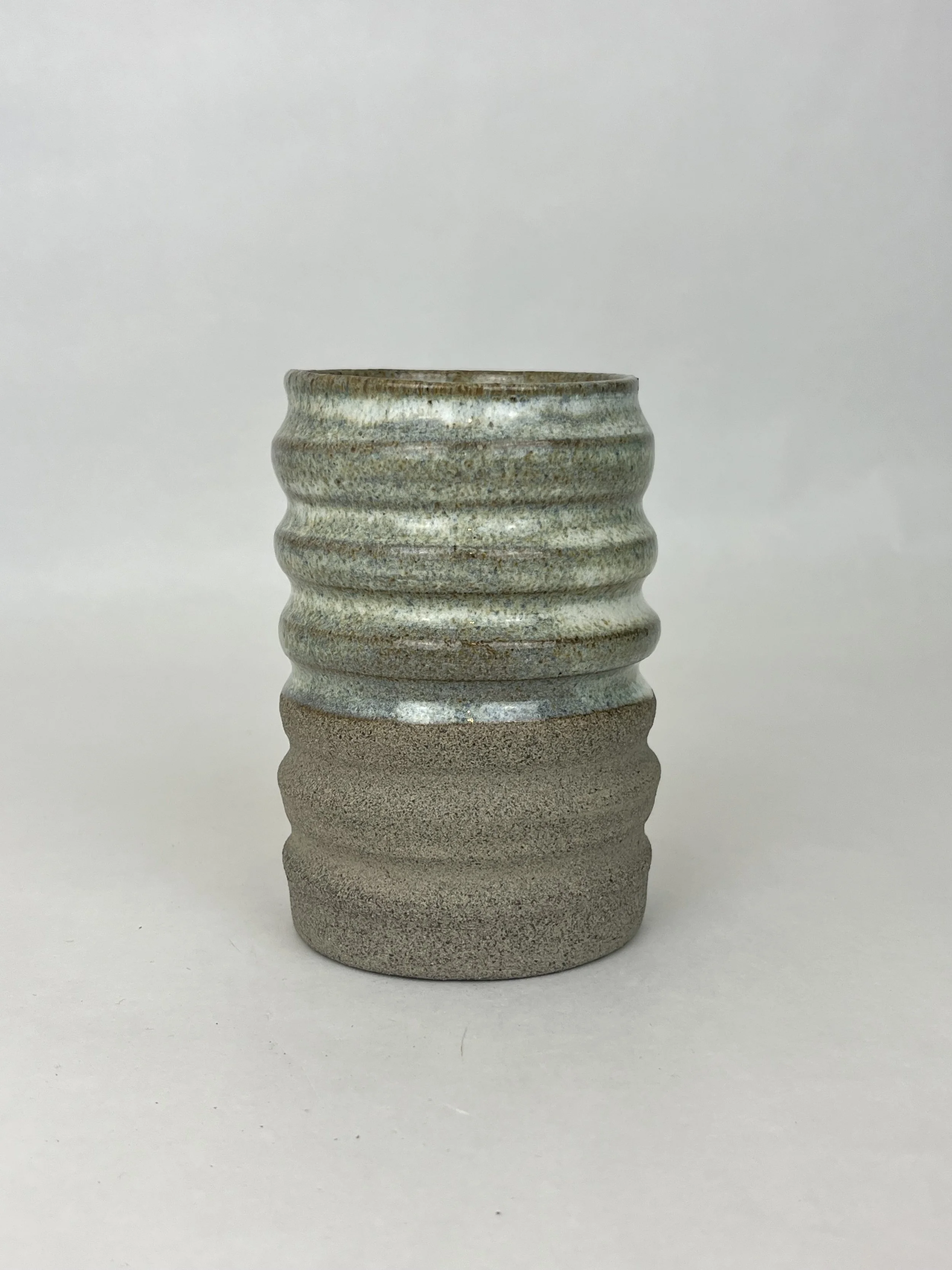 Eine Keramikvase mit abwechselnd glatten und gerippten Oberflächen, in neutralen Farben