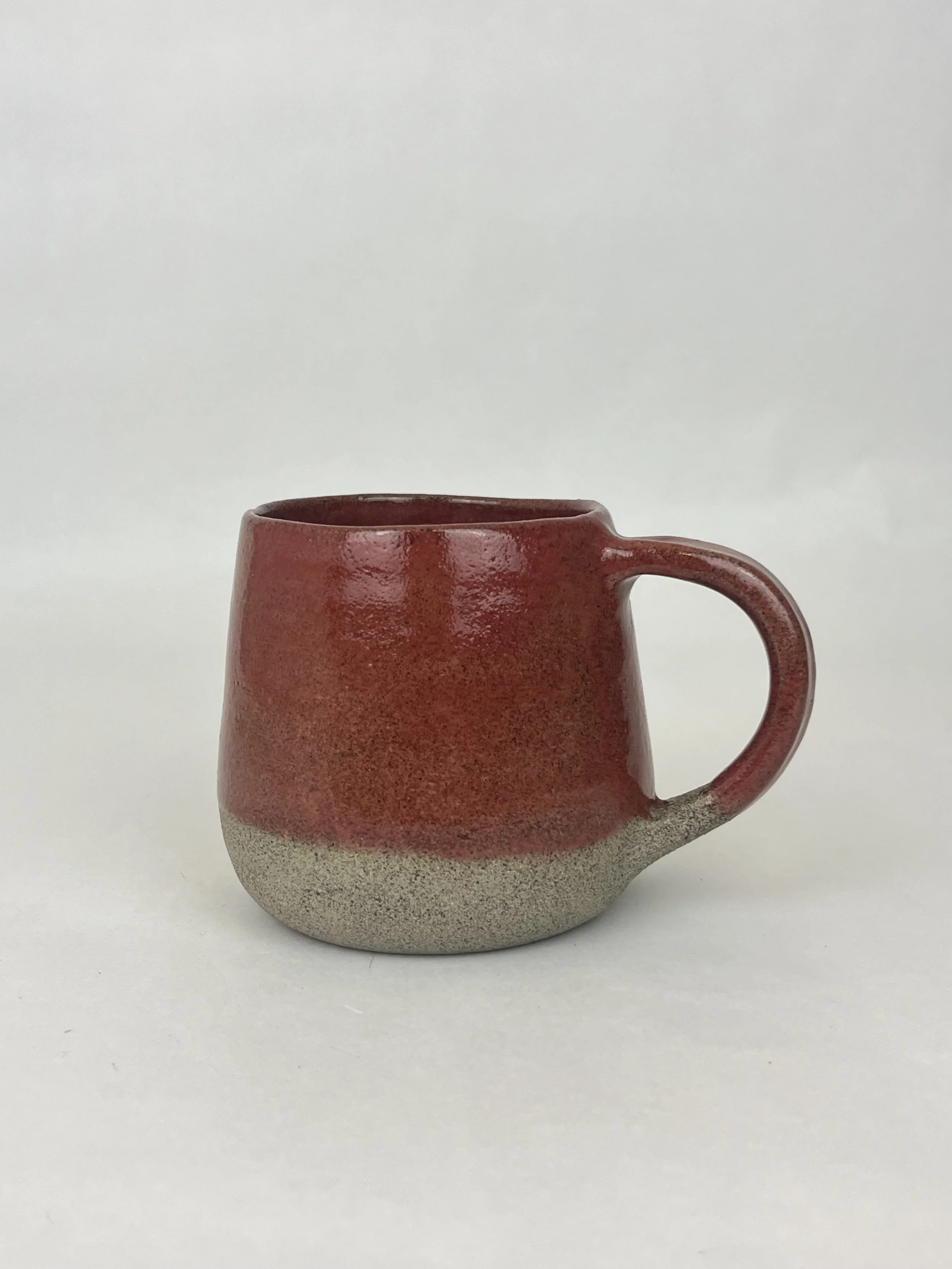 Keramiktasse mit rotem oberen Teil und grauer unterer Hälfte, auf weißem Hintergrund.