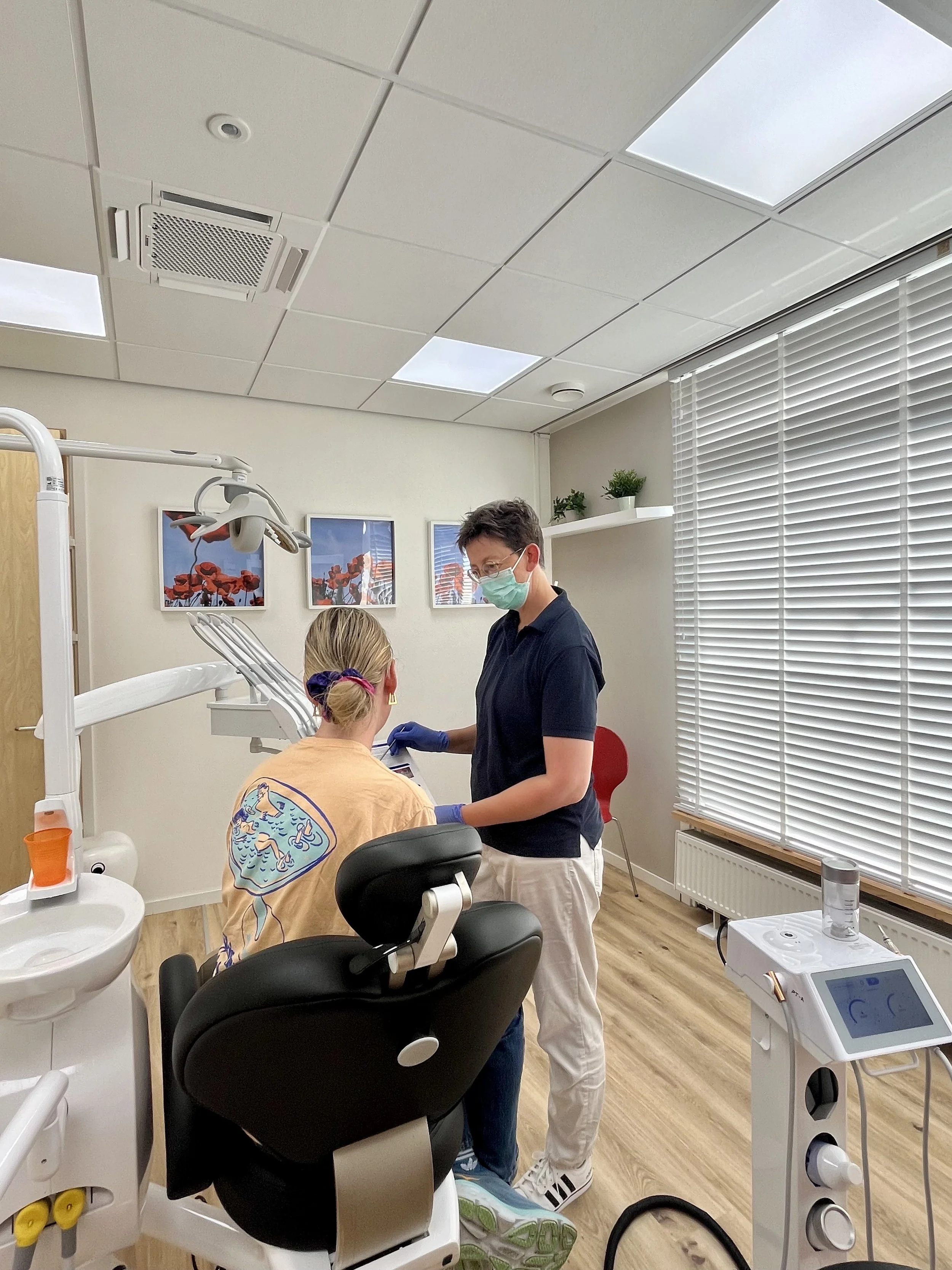 Een tandarts en een patiënt in een tandartspraktijk, met tandheelkundig materiaal en apparatuur.