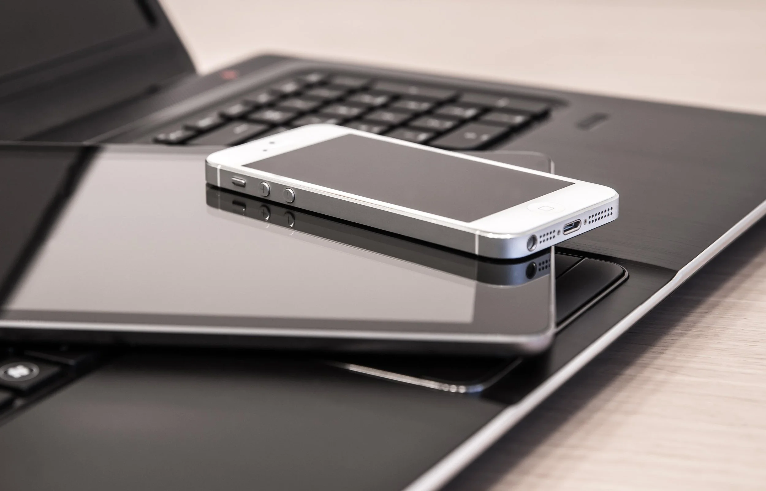 Smarttelefon, nettbrett og laptop på skrivebord – digital administrasjon av korttidsutleie