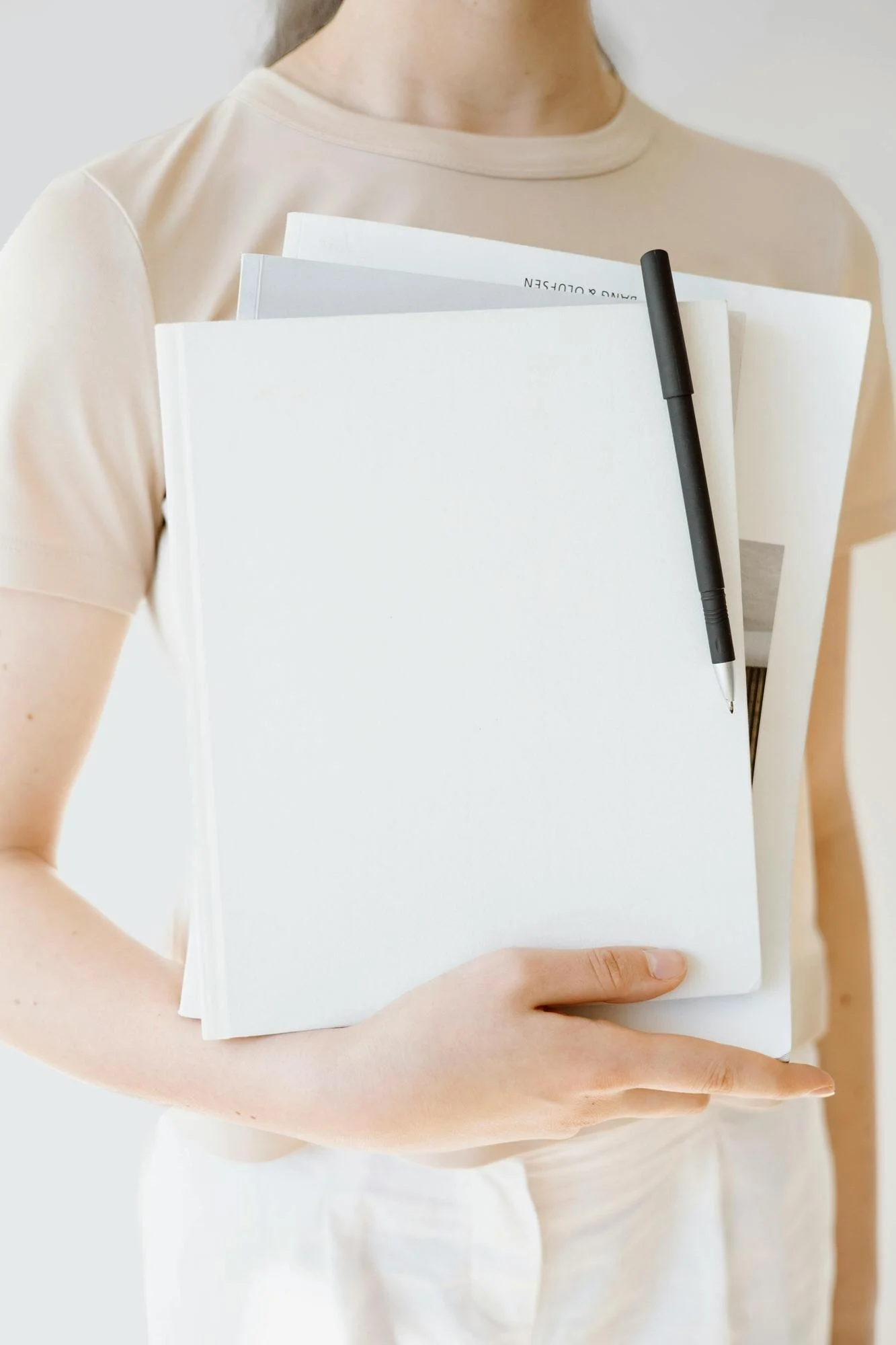 wellness journalist - woman in tan shirt holding papers, notes and a pen to her chest