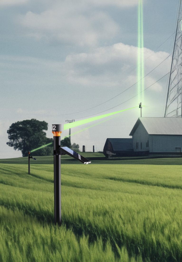 A laser-guided device in a grassy field pointing at a barn in the distance with a laser beam projected through the sky.