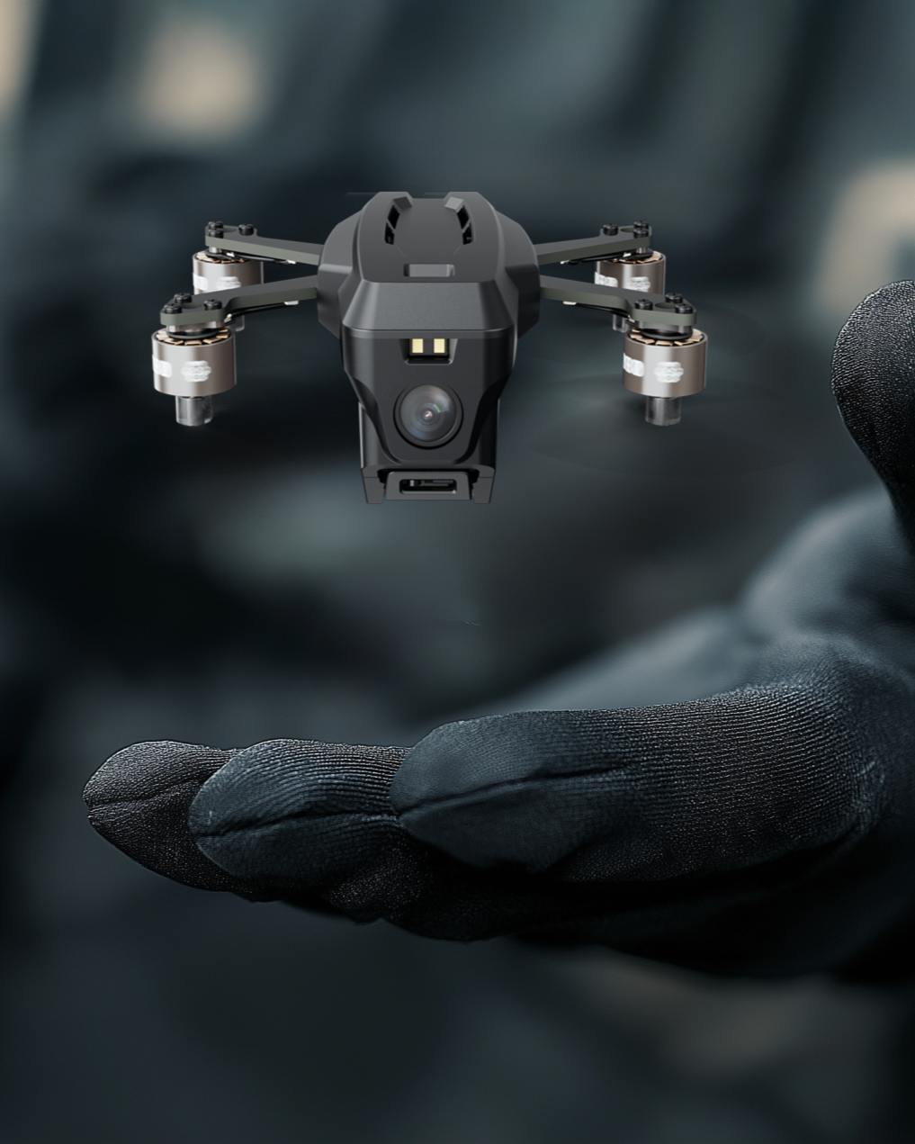 A person wearing black gloves holds a micro Tesseract Nano FPV drone with a camera mounted on the front.
