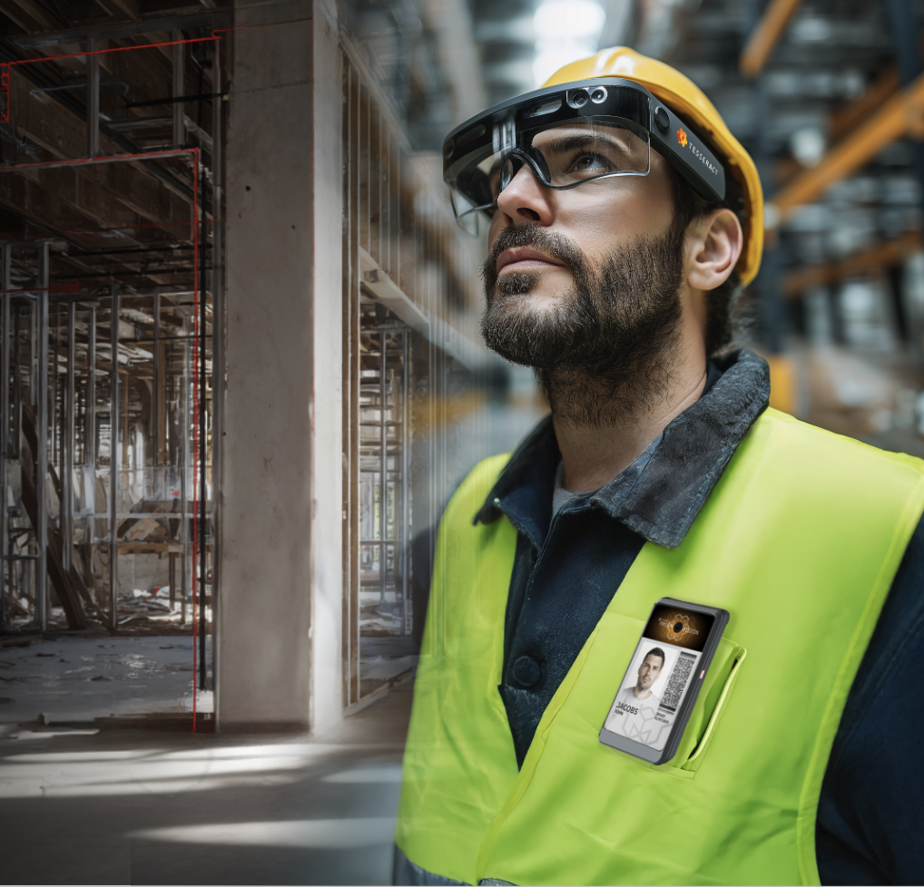A construction worker wearing a yellow safety vest, hard hat, and VR glasses, standing inside an industrial building with framing and construction materials in the background, with a smartphone displaying a Tesseract Site Capture badge.