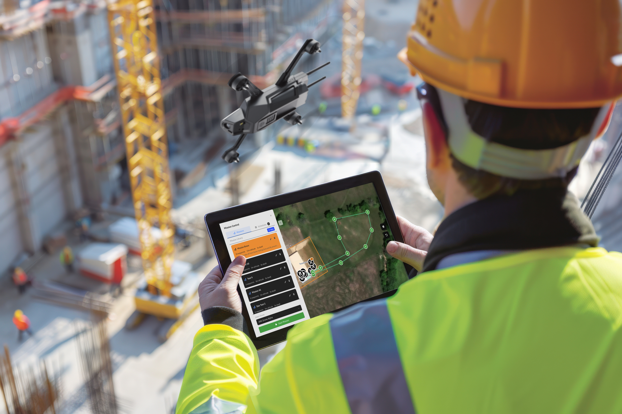 A construction worker in a yellow safety vest and helmet operating a tablet with a drone flying nearby at a construction site with cranes and building frameworks.