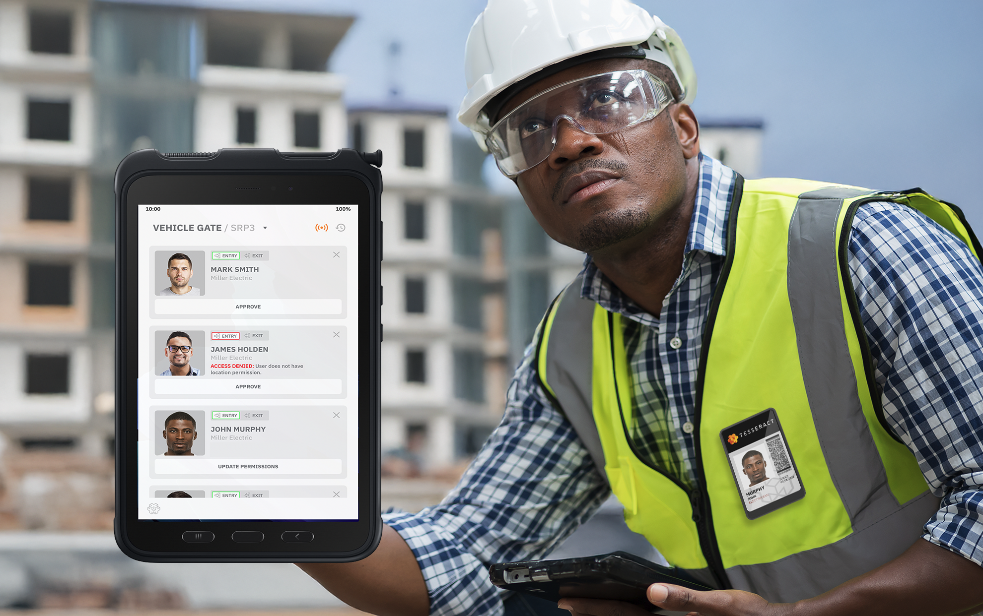 A construction worker outdoors at a building site, wearing a safety helmet and clear safety glasses, holding a tablet displaying the PRISM Dashboard app with photos and statuses of workers, including drive entries, exits, and permission updates.