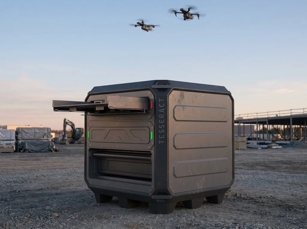A rugged autonomous delivery robot with the label 'TESSERACT' on its side, situated outdoors on a dirt surface with construction equipment and structures in the background, and two drones flying in the sky above.