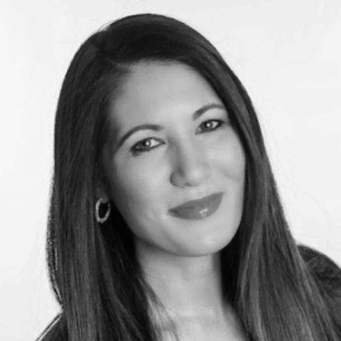 Black and white portrait of a woman with long straight hair, smiling slightly, wearing earrings.
