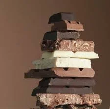 Stack of various chocolate and white confections on a plain background.