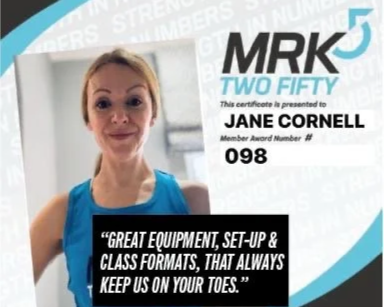 Close-up of a woman in a blue shirt smiling, next to a digital certificate titled 'MRK52 Two Fifty' awarded to Jane Cornell for great equipment, setup, and class formats.