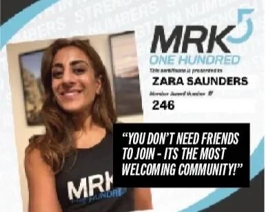 A young woman smiling, wearing a black MRK shirt, stands in front of a certificate or award with the title 'MRK 5'.