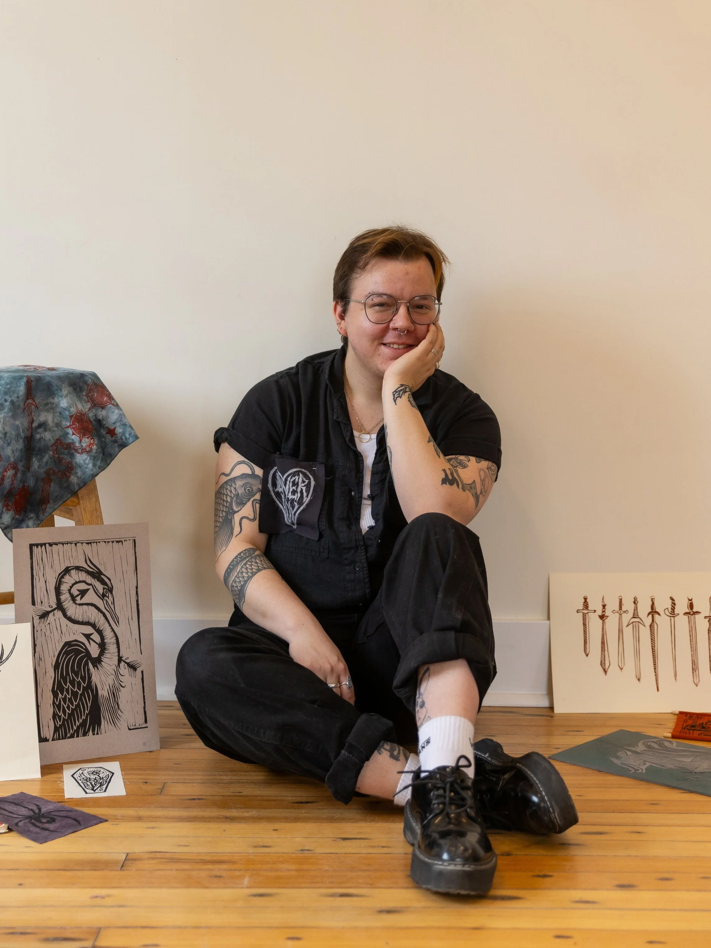 Finnegan West sitting on a wooden floor surrounded by artwork.