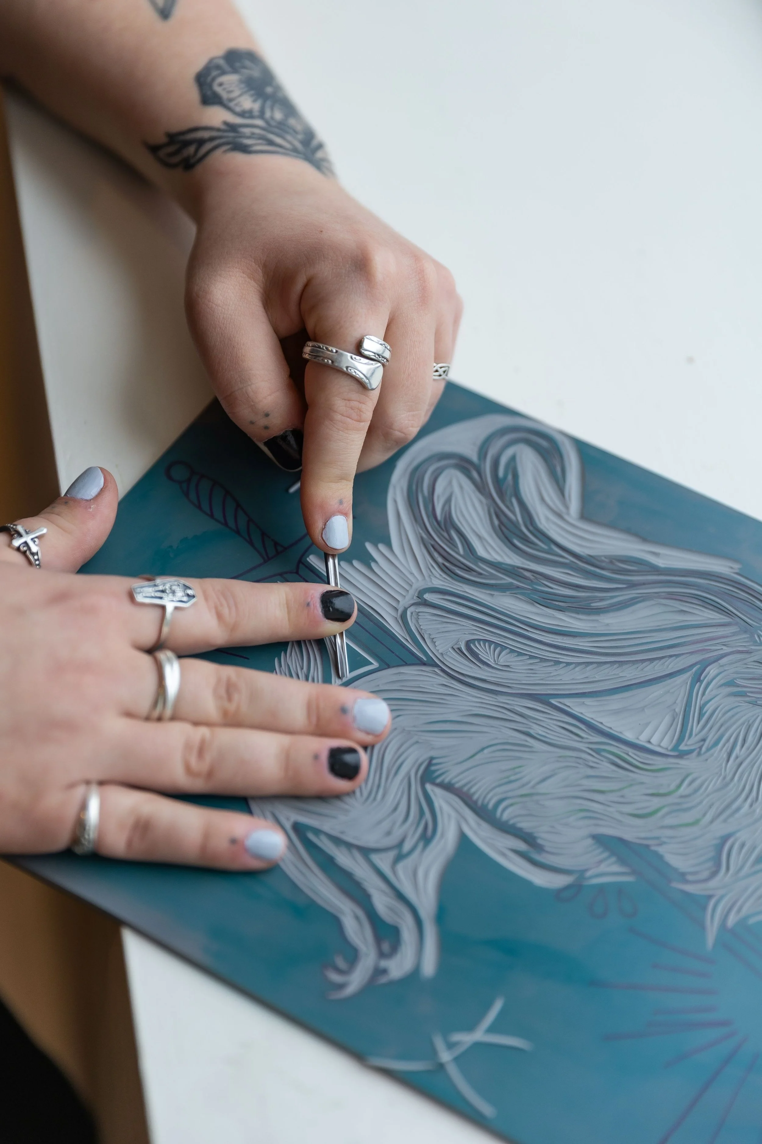 Person creating a woodburning art of a horse on a blue surface, using a hot tool to burn details into the design.