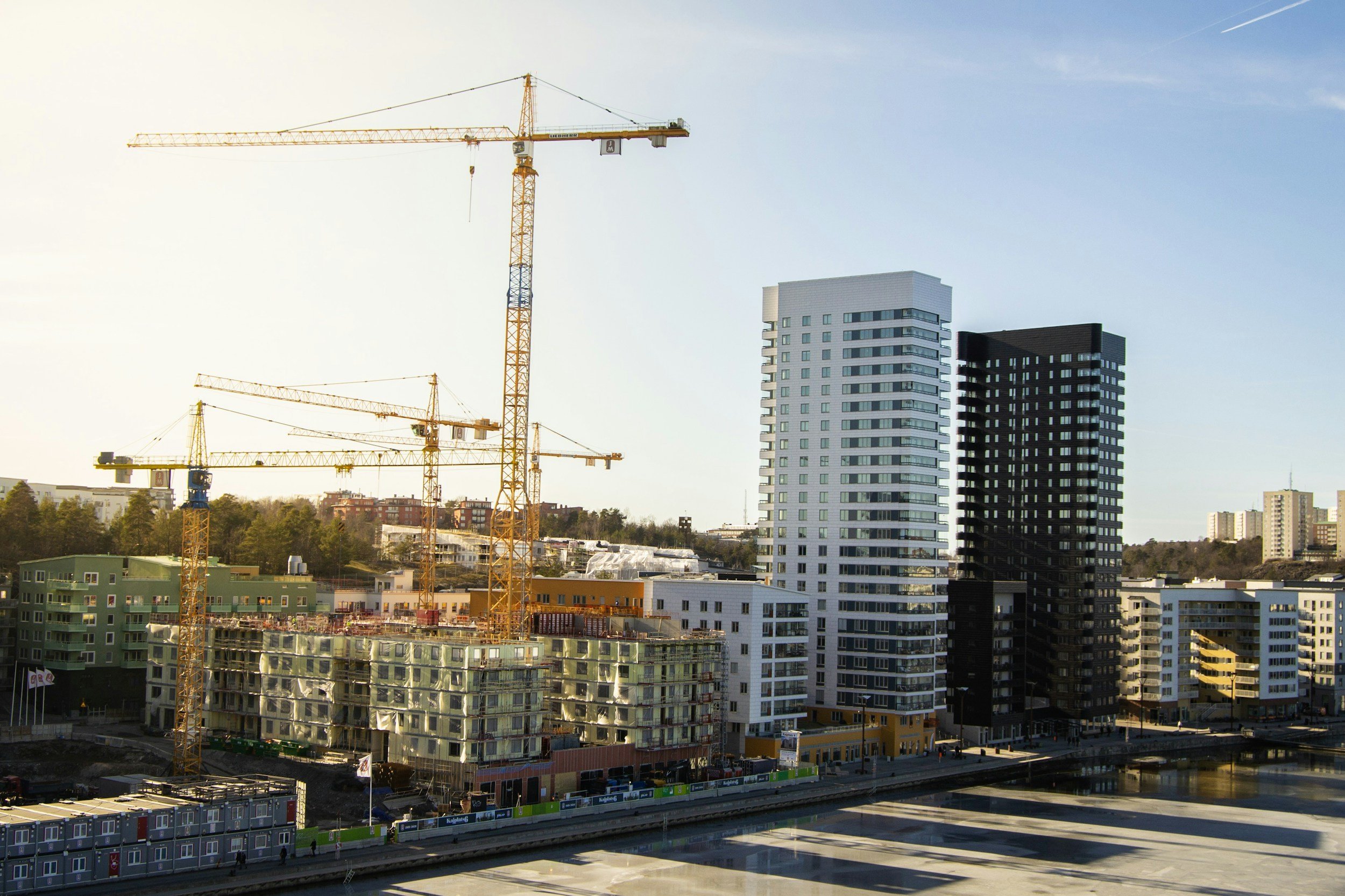 Cityscape with high-rise buildings and construction cranes under a clear sky.