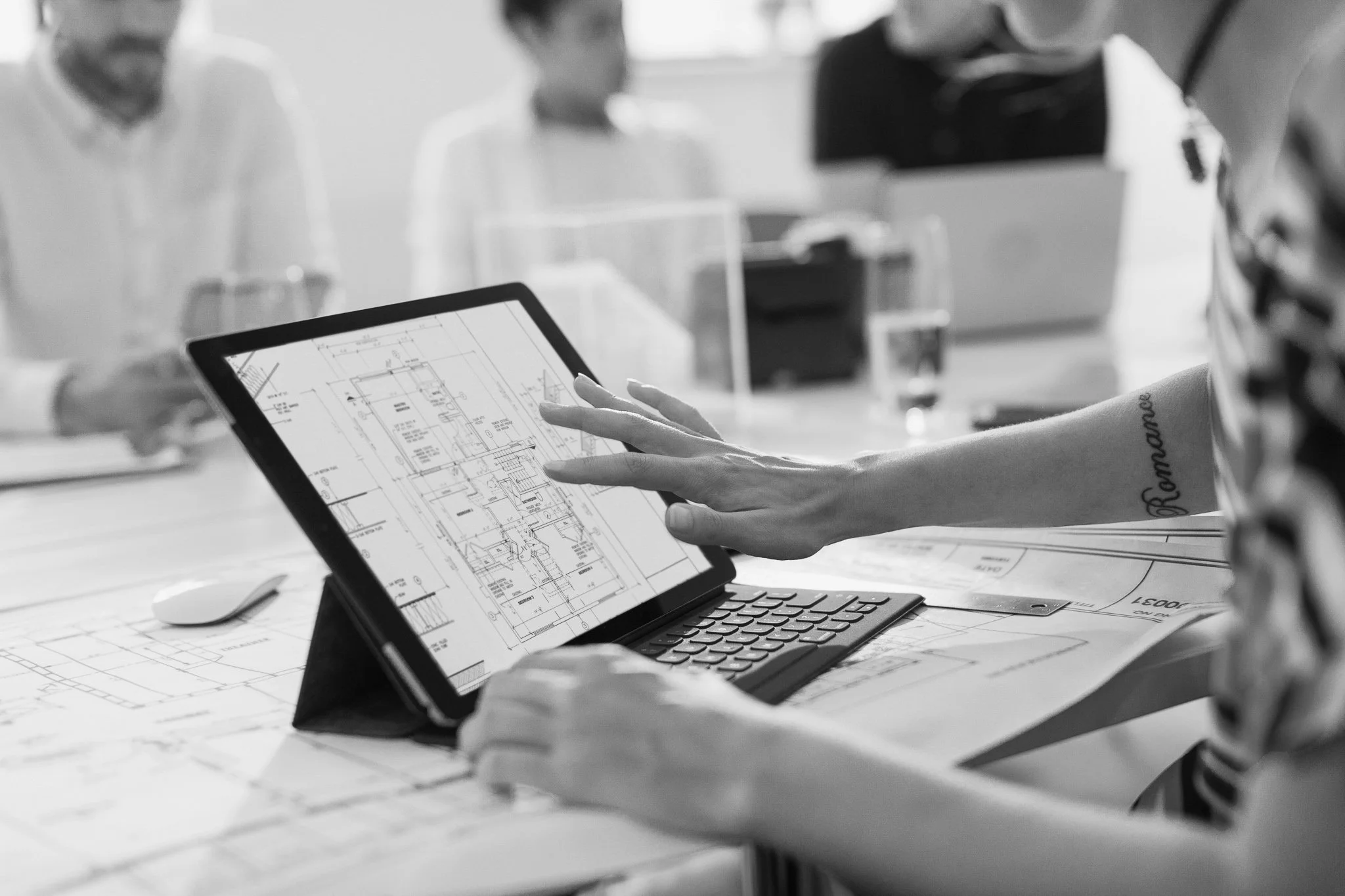 People reviewing architectural plans on a tablet in a meeting room.