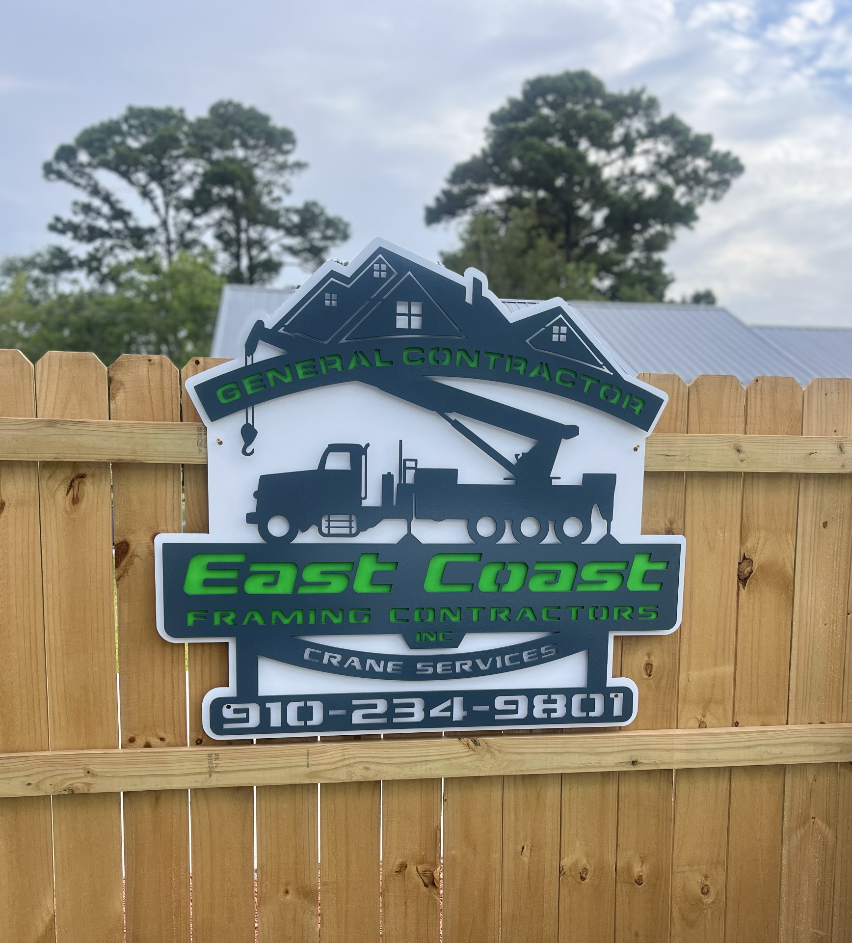 Sign for East Coast Framing Contractors Inc. showing a truck with a crane and houses in the background