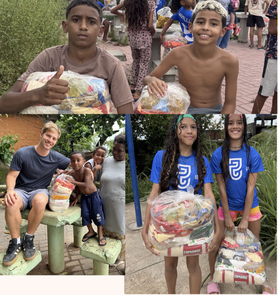 Children and young adults participating in a food donation event, holding bags of food in an outdoor setting with trees and brick structures.