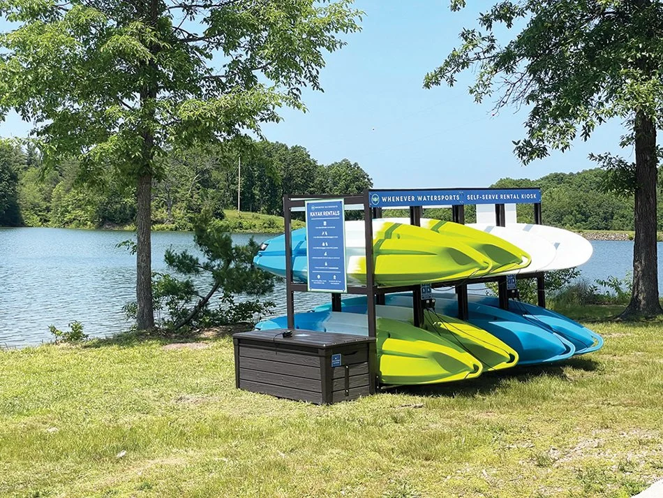 a stack of kayaks on the shore of a lake
