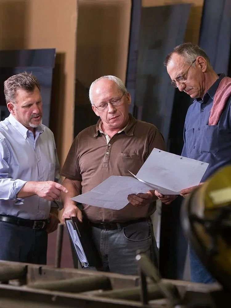 Gillespie Corporation closely examining papers or blueprints.