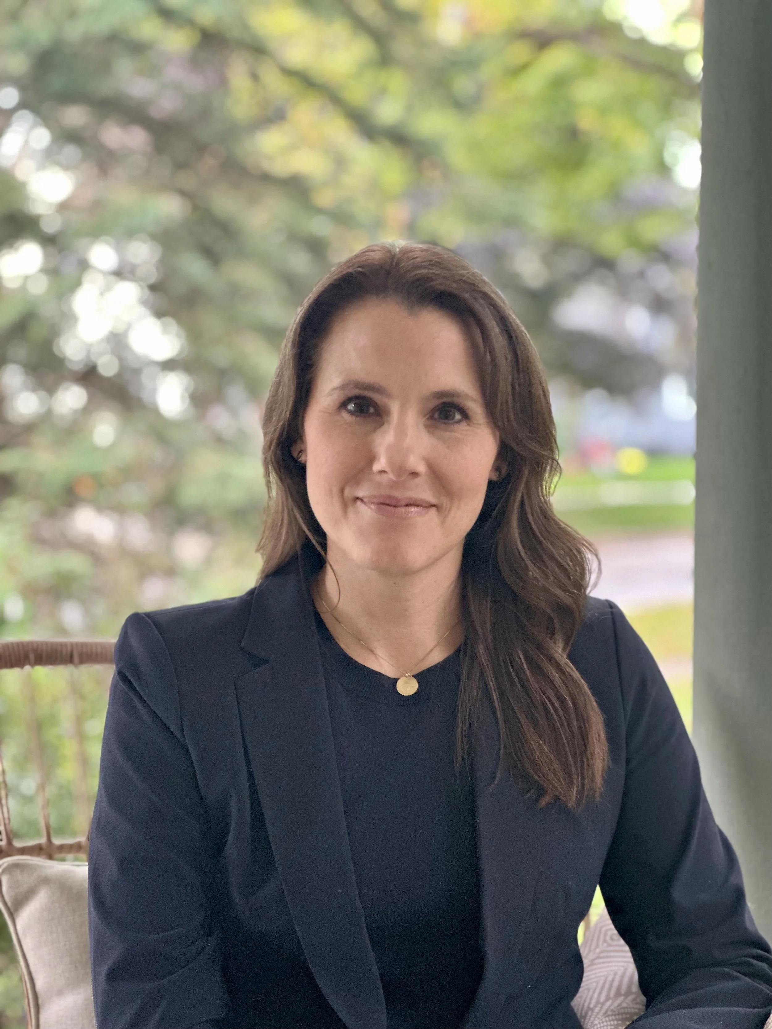April in a navy suit outdoors on a porch