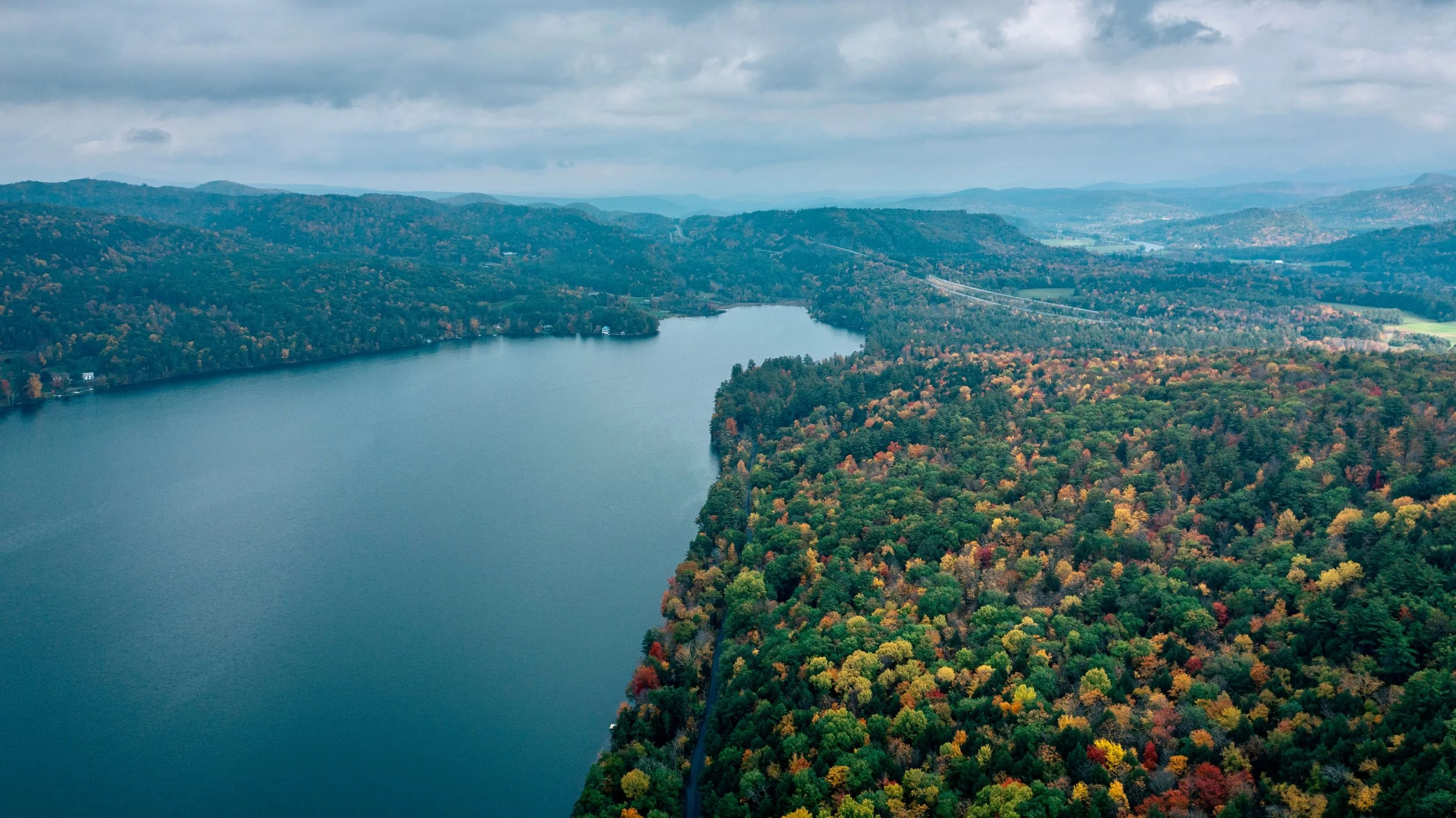 Aerial drone shot of colorful autumn trees along a river.