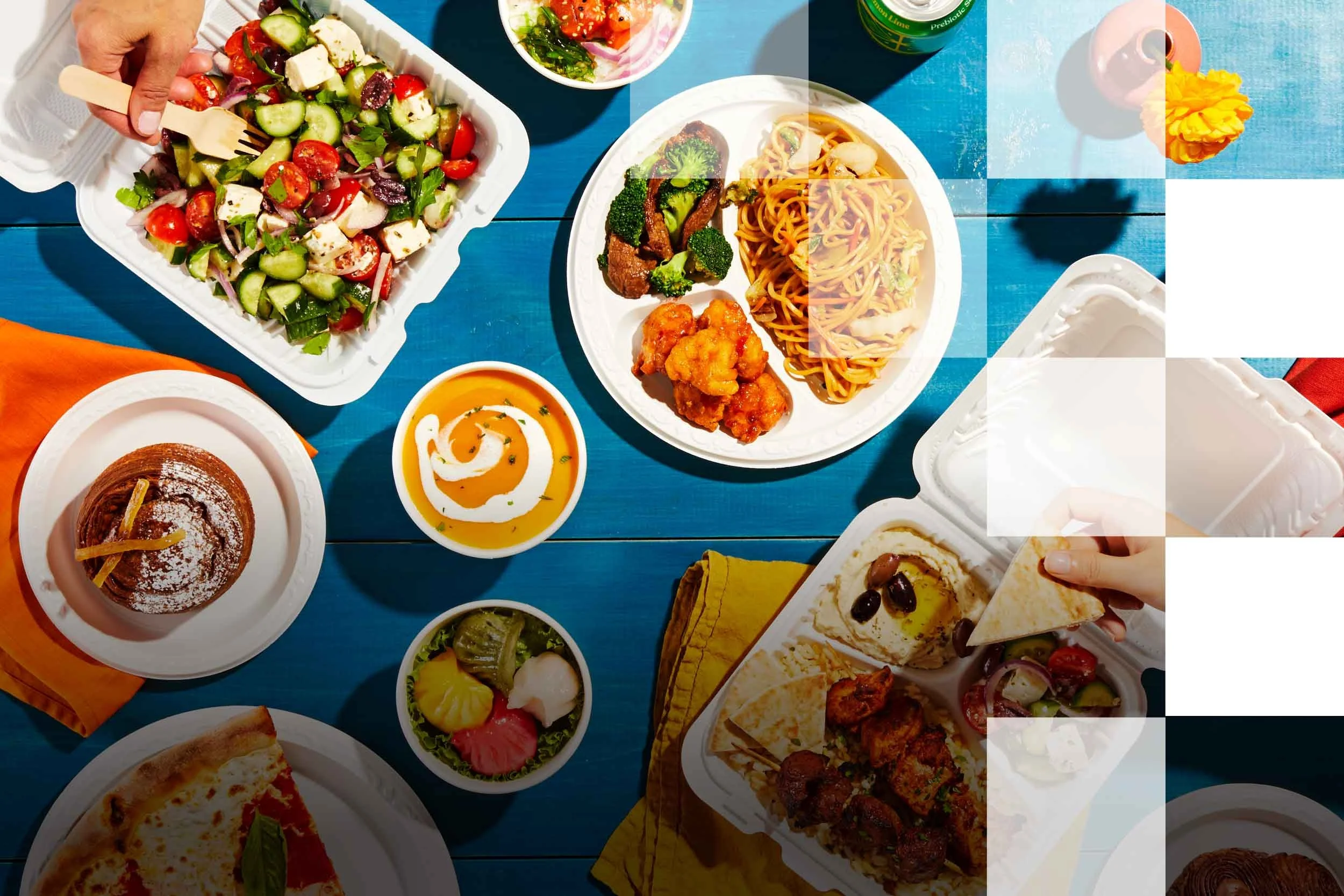 A variety of foods on a blue table including salad, pasta, chicken, dessert, and drinks.