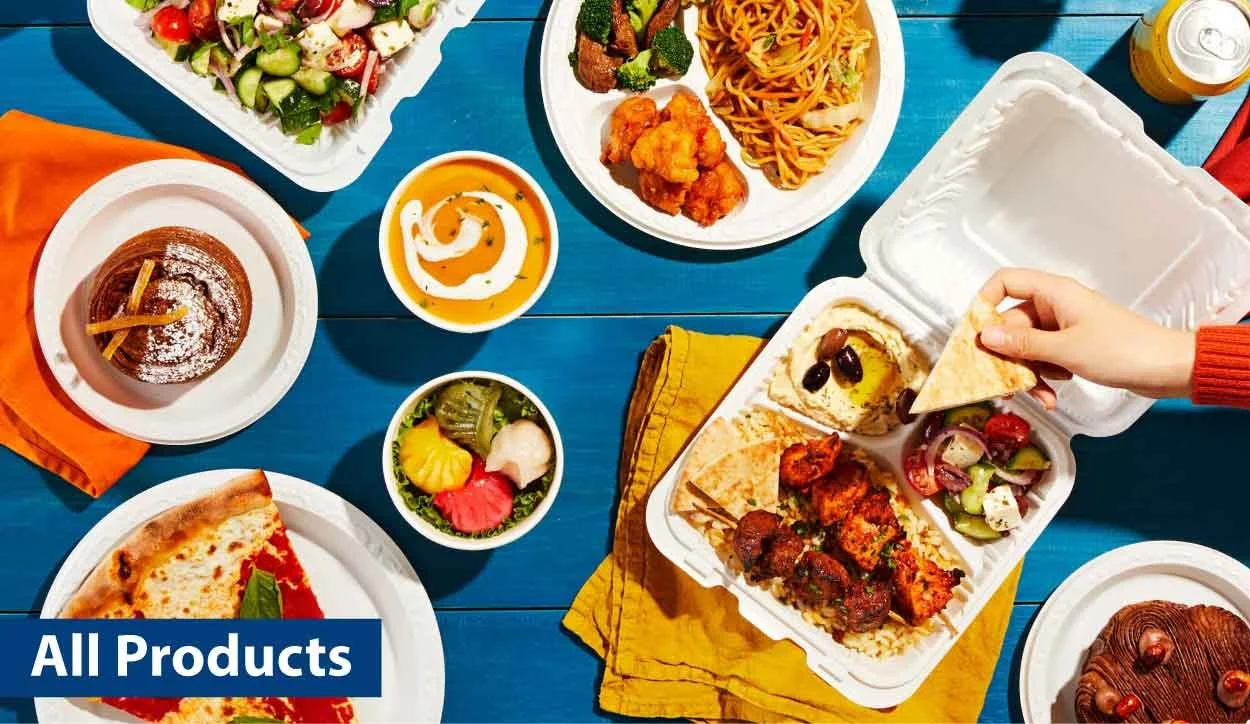 Assorted fast food dishes including pizza, pasta, salad, hummus, falafel, skewers, desserts, and drinks on a blue table.