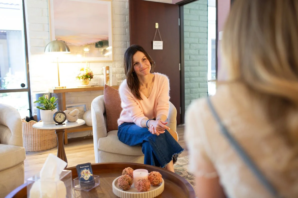 Rebecca Tofield smiling in a therapy session with a woman in a light-colored top in a cozy office.