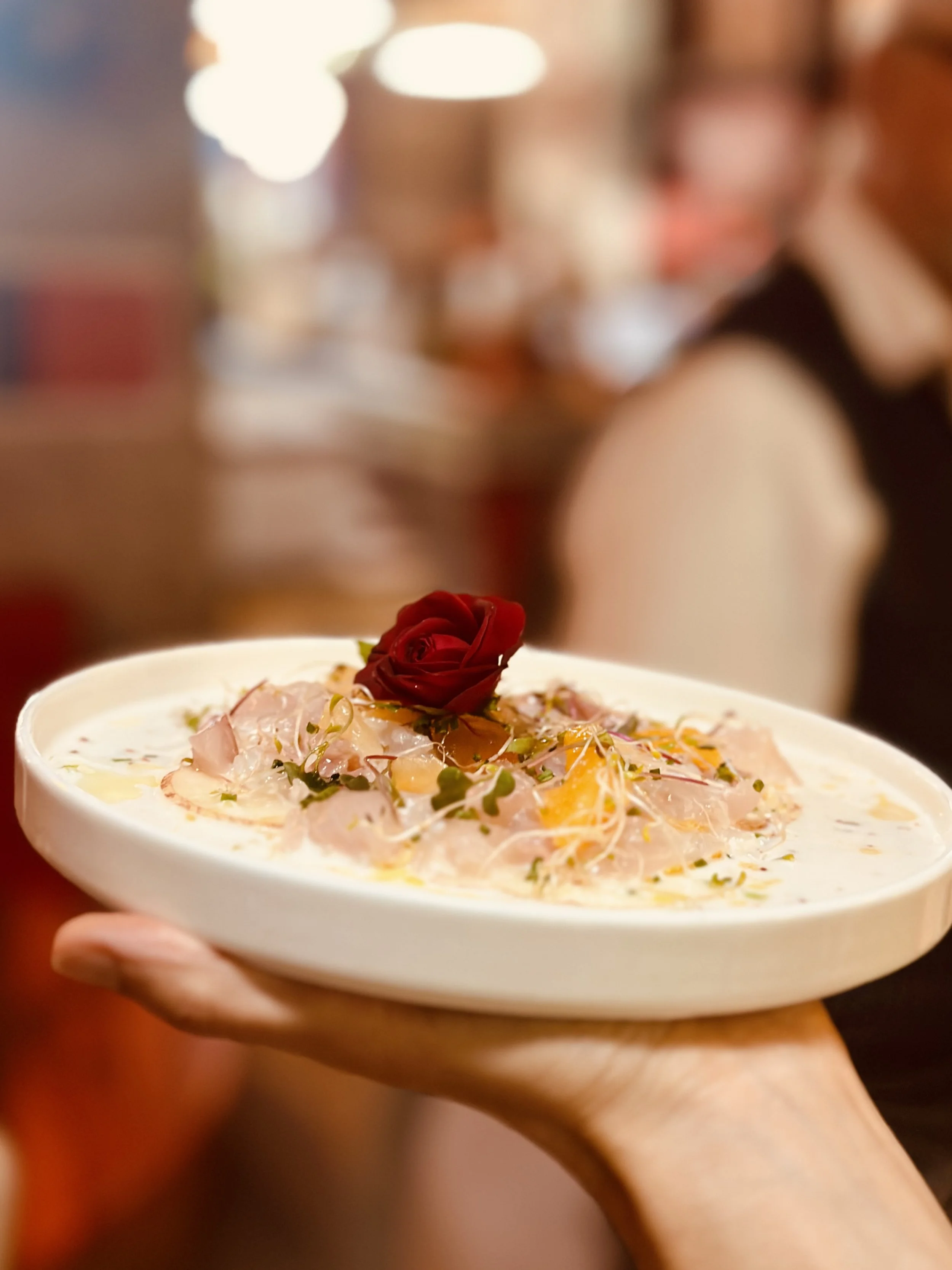 Chez Jaillet Lyon 6 | Un ceviche de Dorades servi par Didier Jaillet avec des graines, des herbes, et une rose rouge sur le dessus.