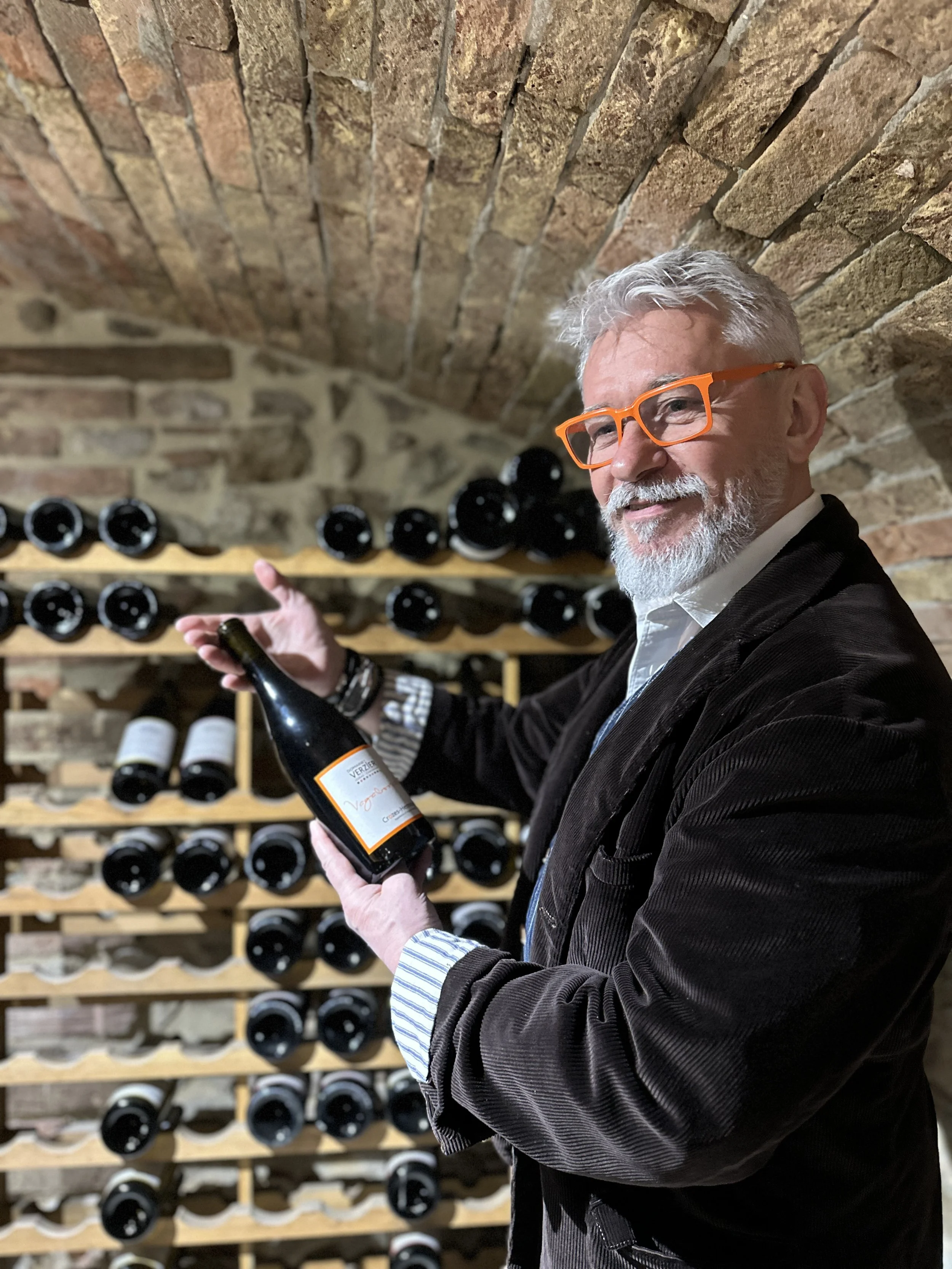 Chez Jaillet Lyon 6 | Didier Jaillet tient une bouteille de vin dans une cave à vin en pierre lors d'une visite chez son vigneron.