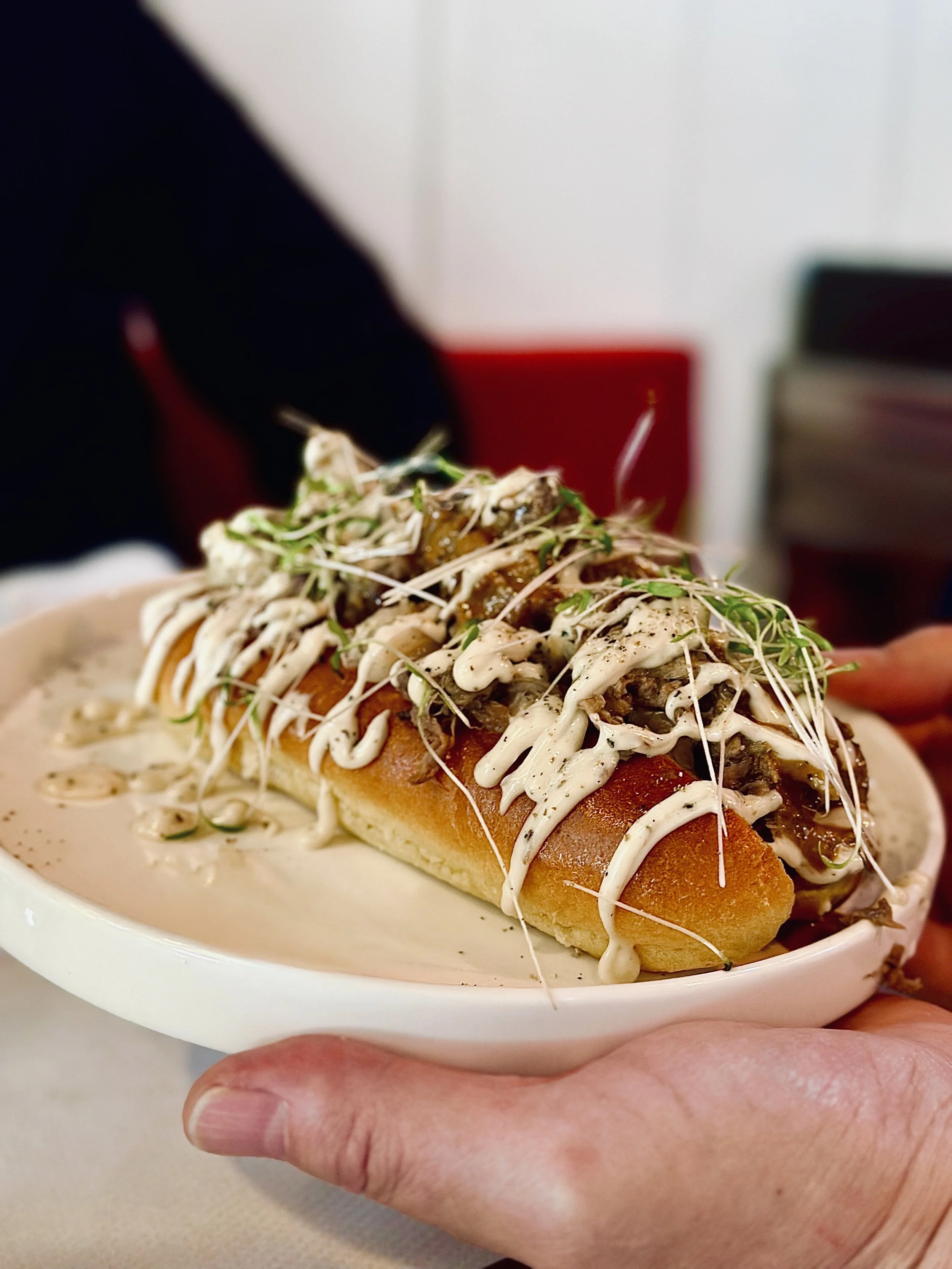 Chez Jaillet Lyon 6 | Une assiette Hot Dog façon gastronomique garni de légumes, de sauce et de graines, au Bistrot Lyon 6.