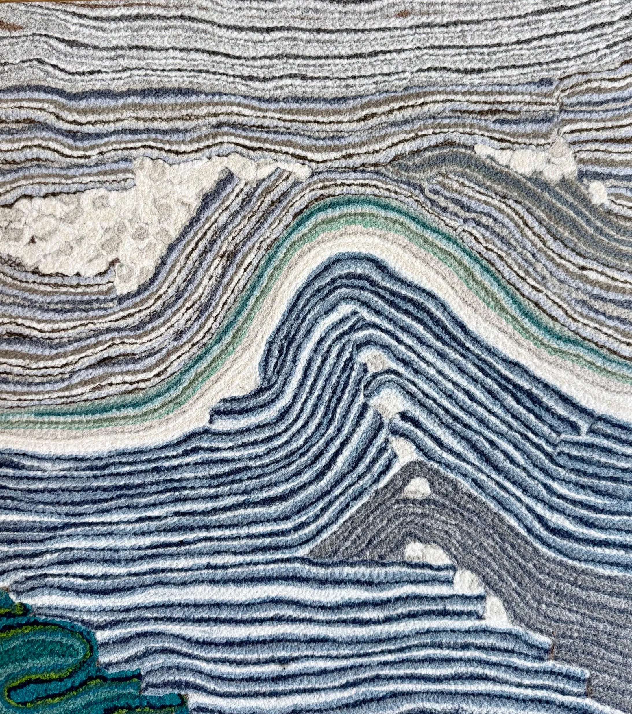 A close-up view of a textured fabric with multicolored, wavy, embroidered lines and patterns.