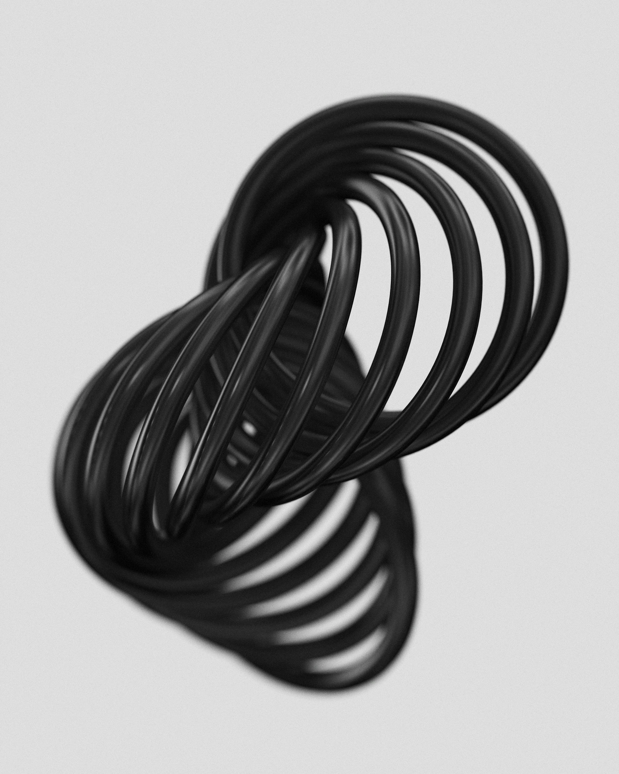 Close-up of a black metal spring coil against a plain light gray background.