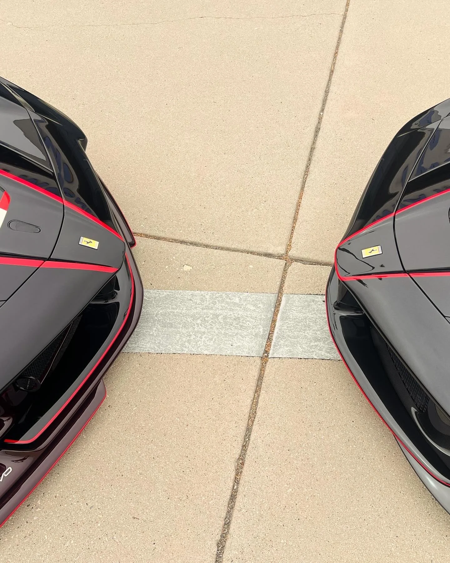 Two black sports cars with red accents parked facing each other on a sidewalk.