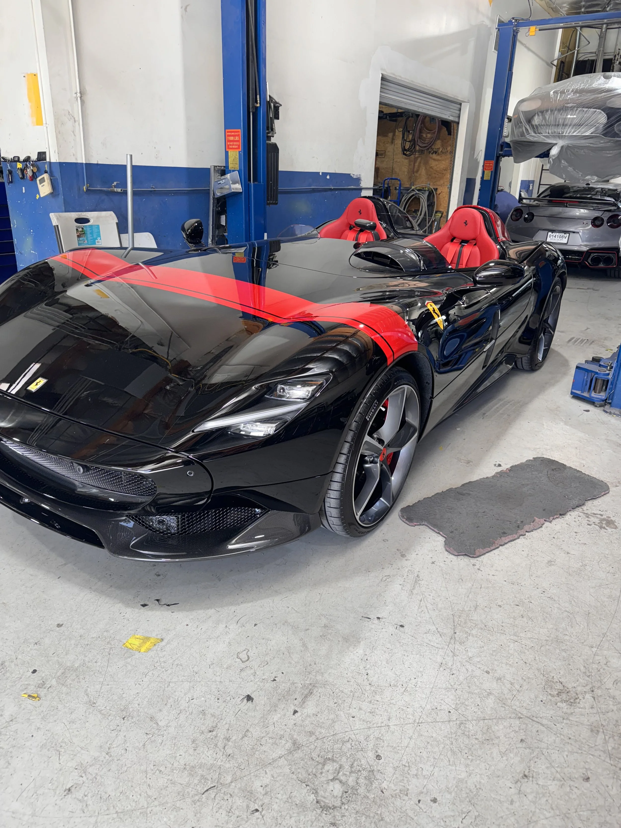 A black race car with red accents and red interior seats parked in a garage.