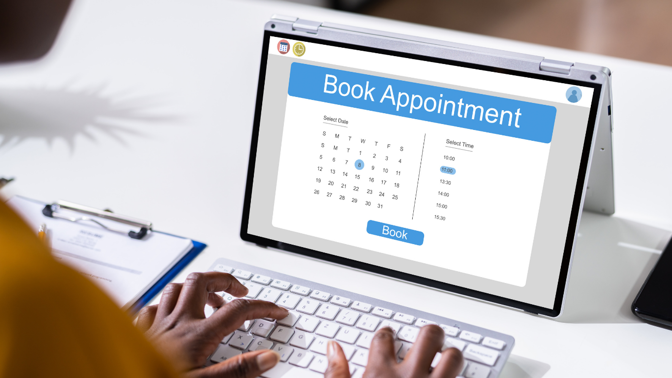 Person booking an appointment on a laptop with a calendar interface on the screen.